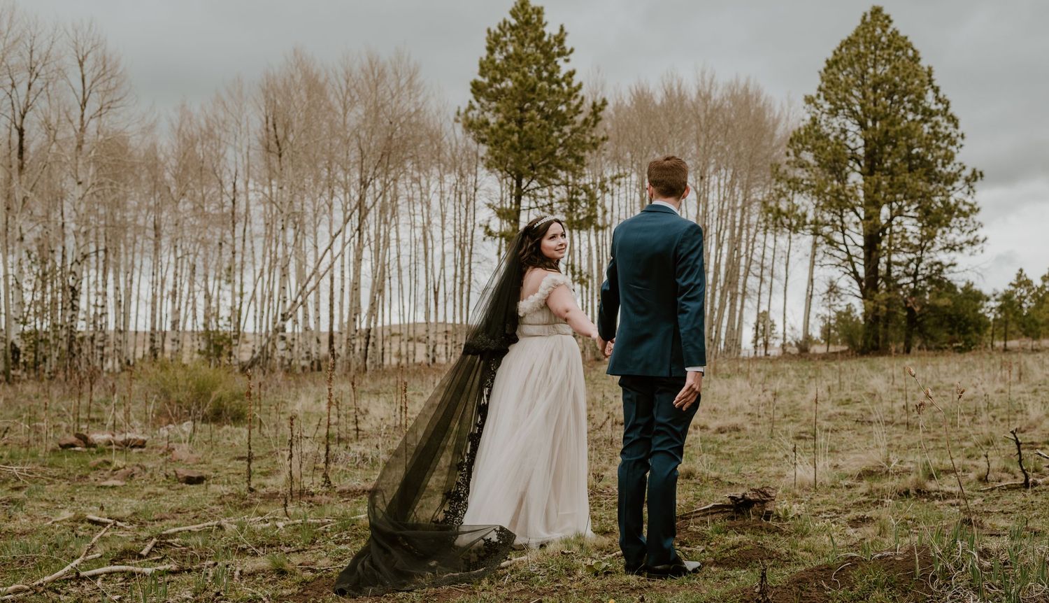 A scenic wedding photo with towering aspen trees creating a dramatic natural backdrop.