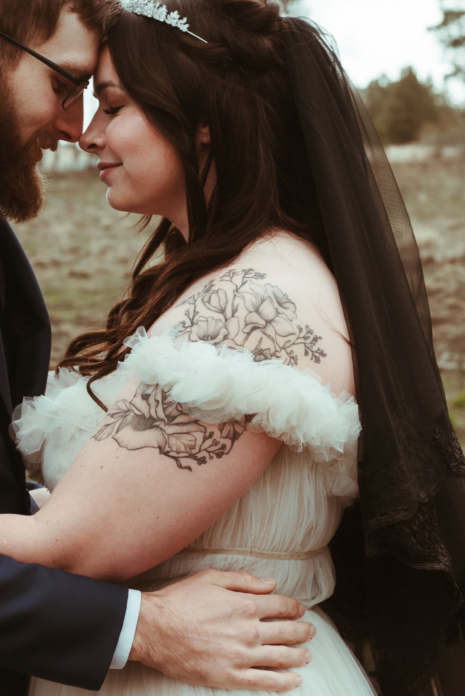 A couple embraces while the bride wears a delicate white dress with embroidered details.