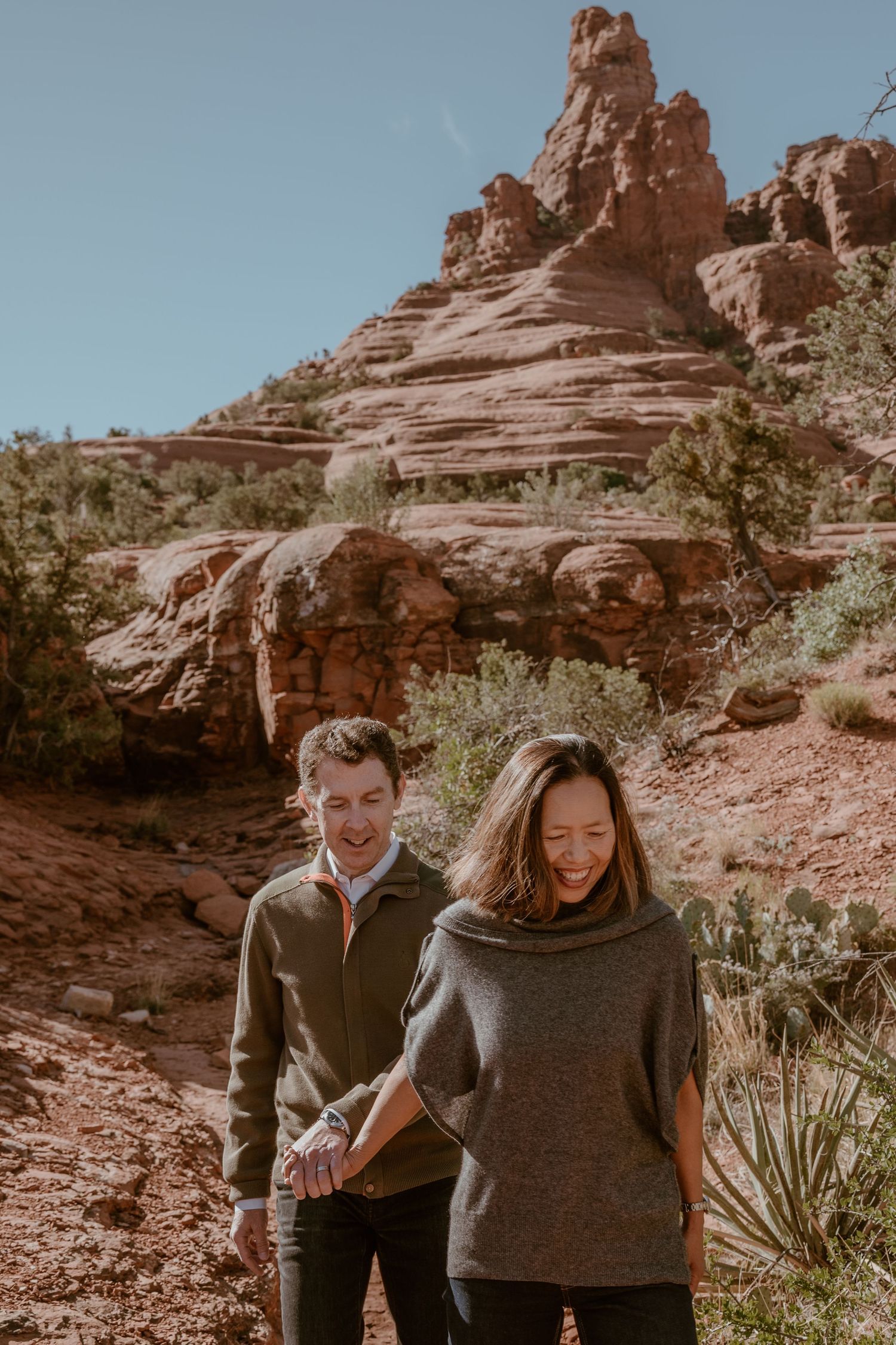 Couple walking together among desert rock formations and cacti.