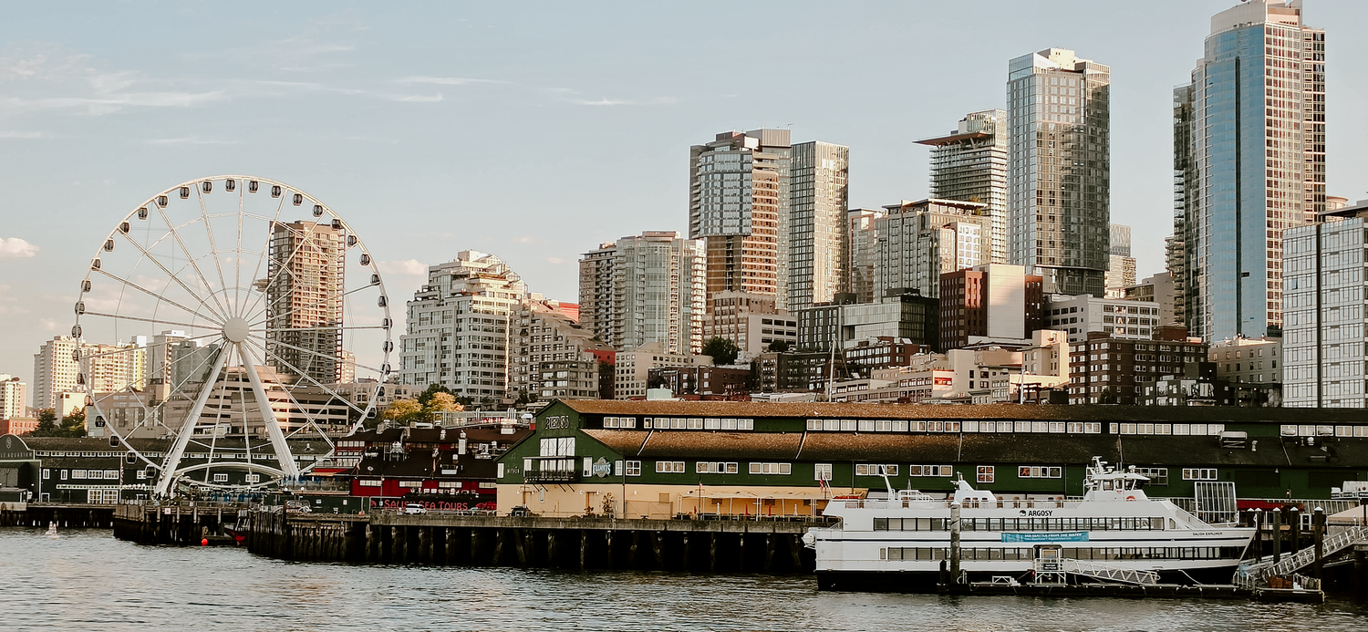 Seattle waterfront skyline with iconic Great Wheel ferris wheel, modern skyscrapers, and ferry boat on Elliott Bay.