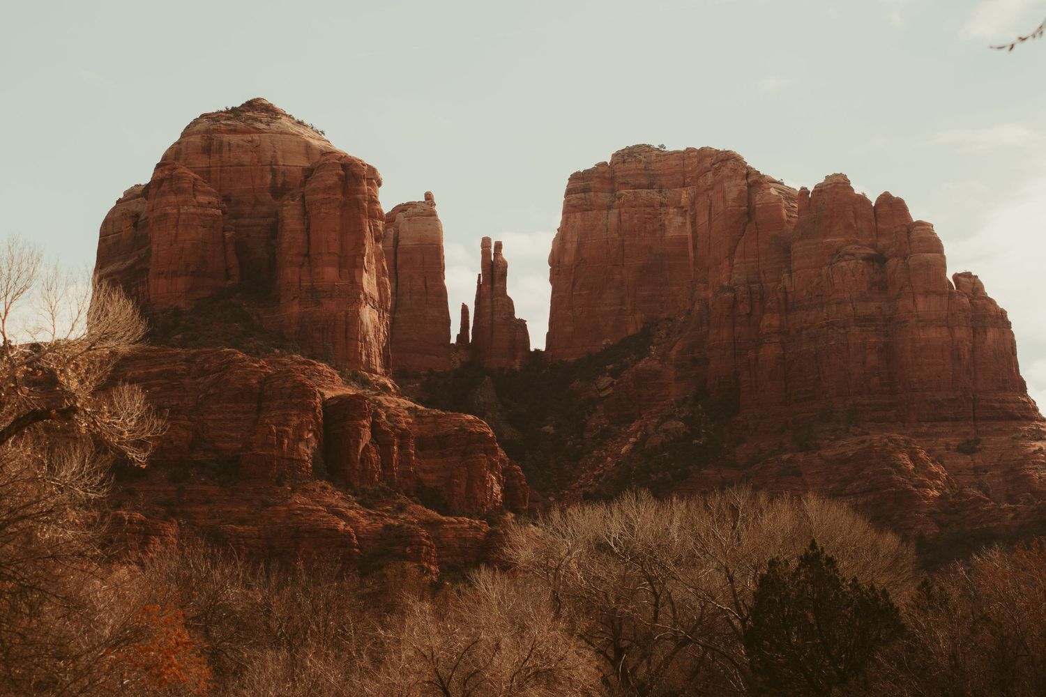 Red rock formations rise dramatically against the sky in Sedona's desert landscape.