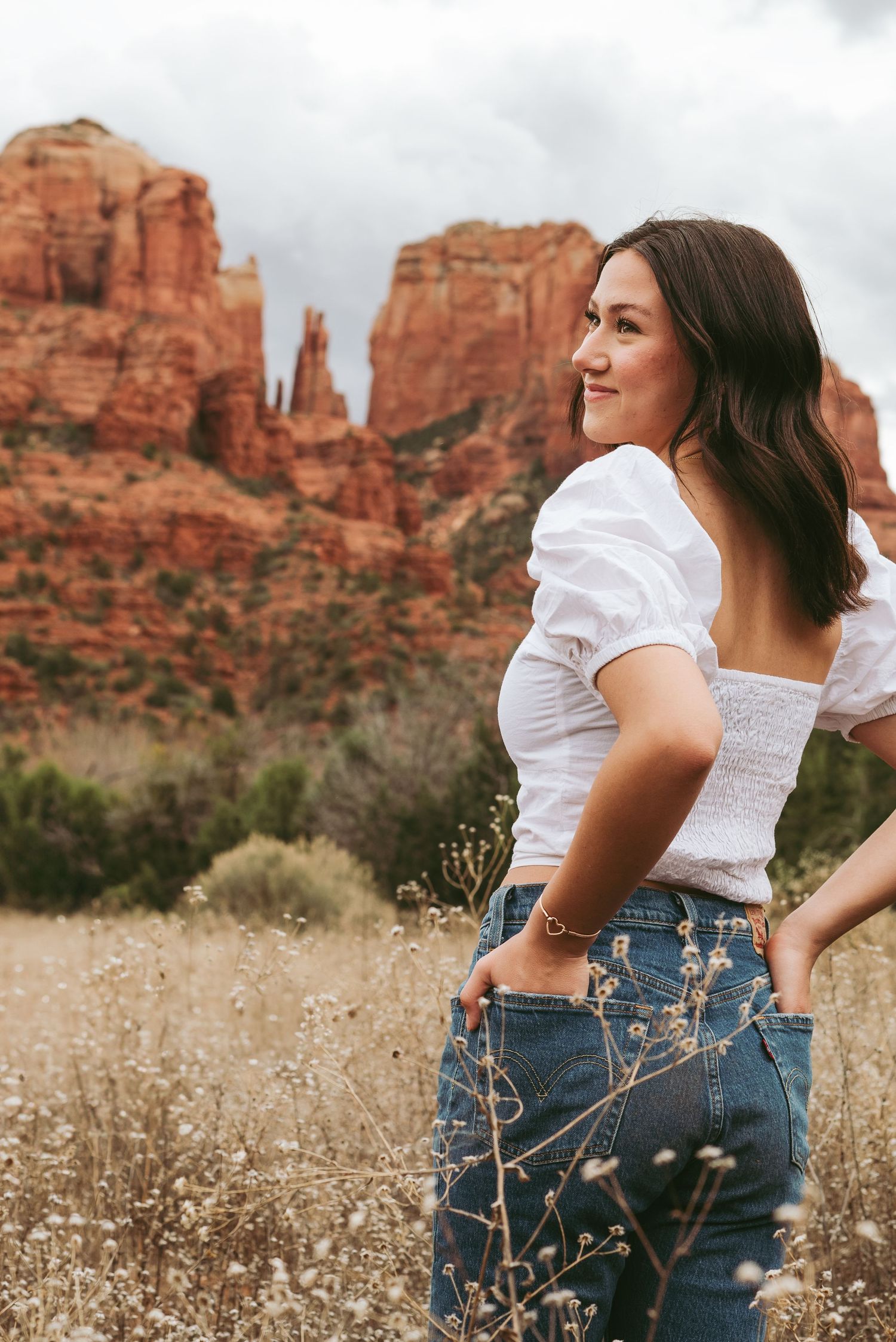 White puff sleeve top and jeans styled against Sedona's red rock landscape.