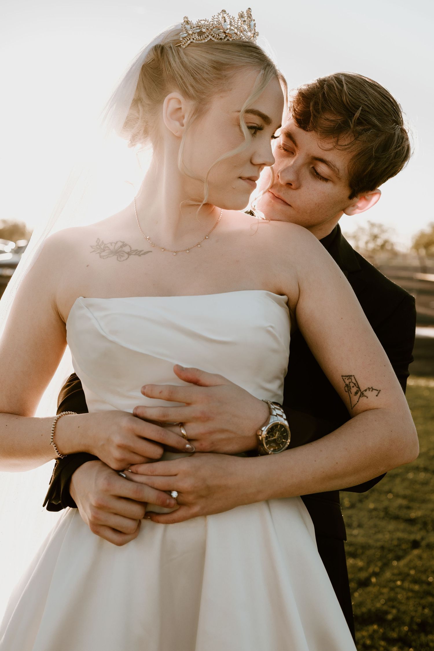 An intimate wedding moment captured in warm sunlight with elegant formal attire and delicate details.