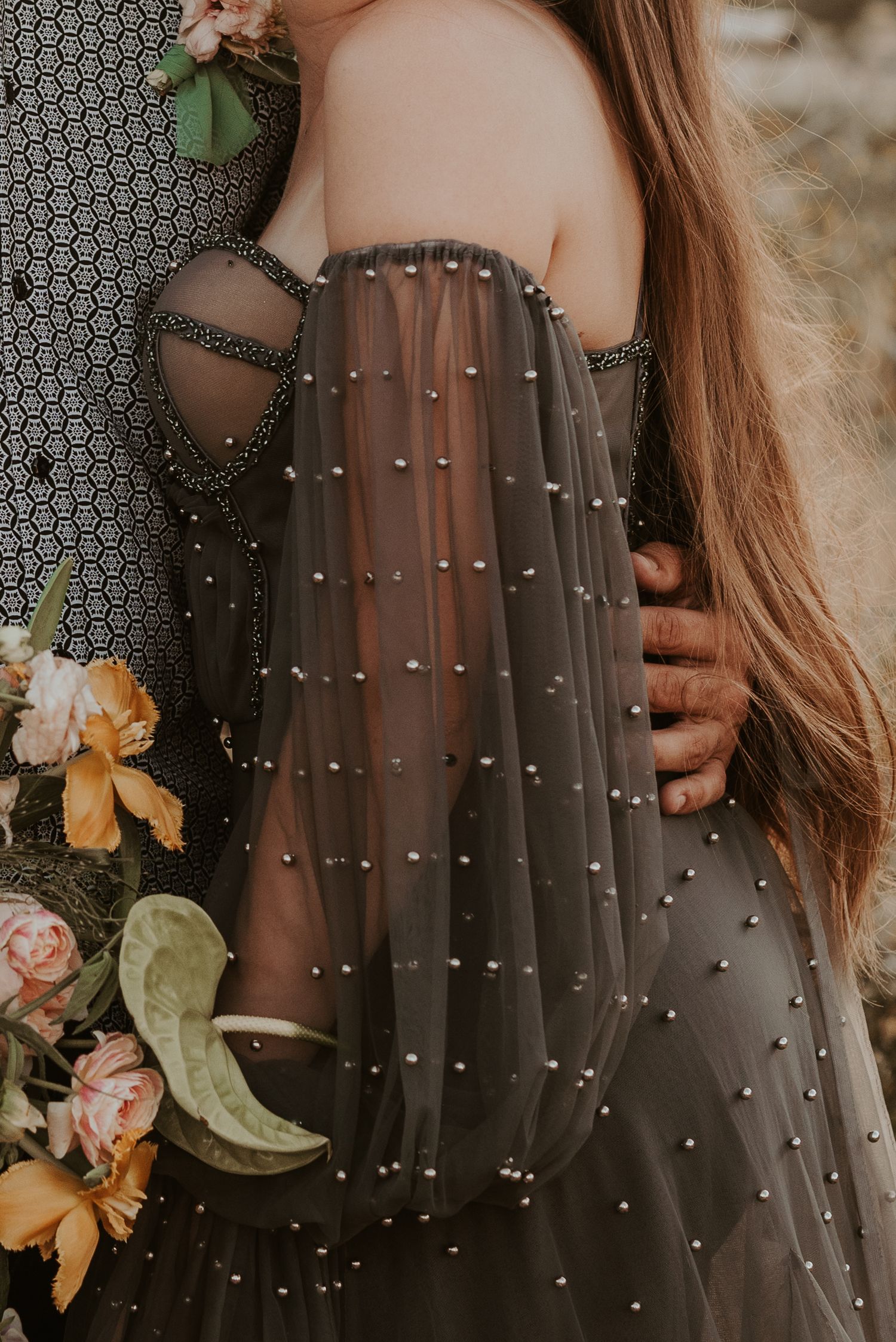 Detail shot of pearl-studded gray dress with florals in soft focus.