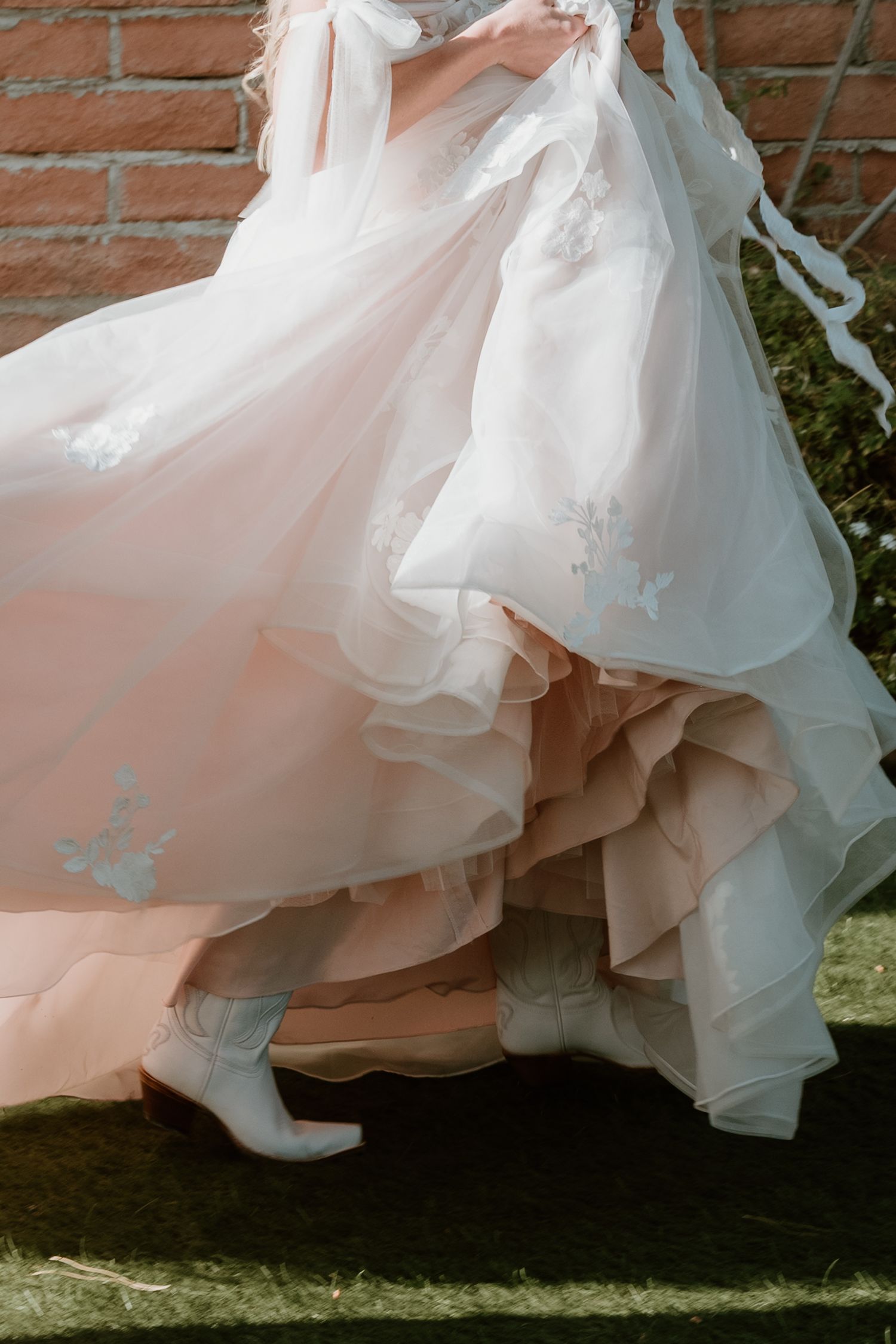 Sequence of white wedding dress flowing in movement against a brick wall backdrop.