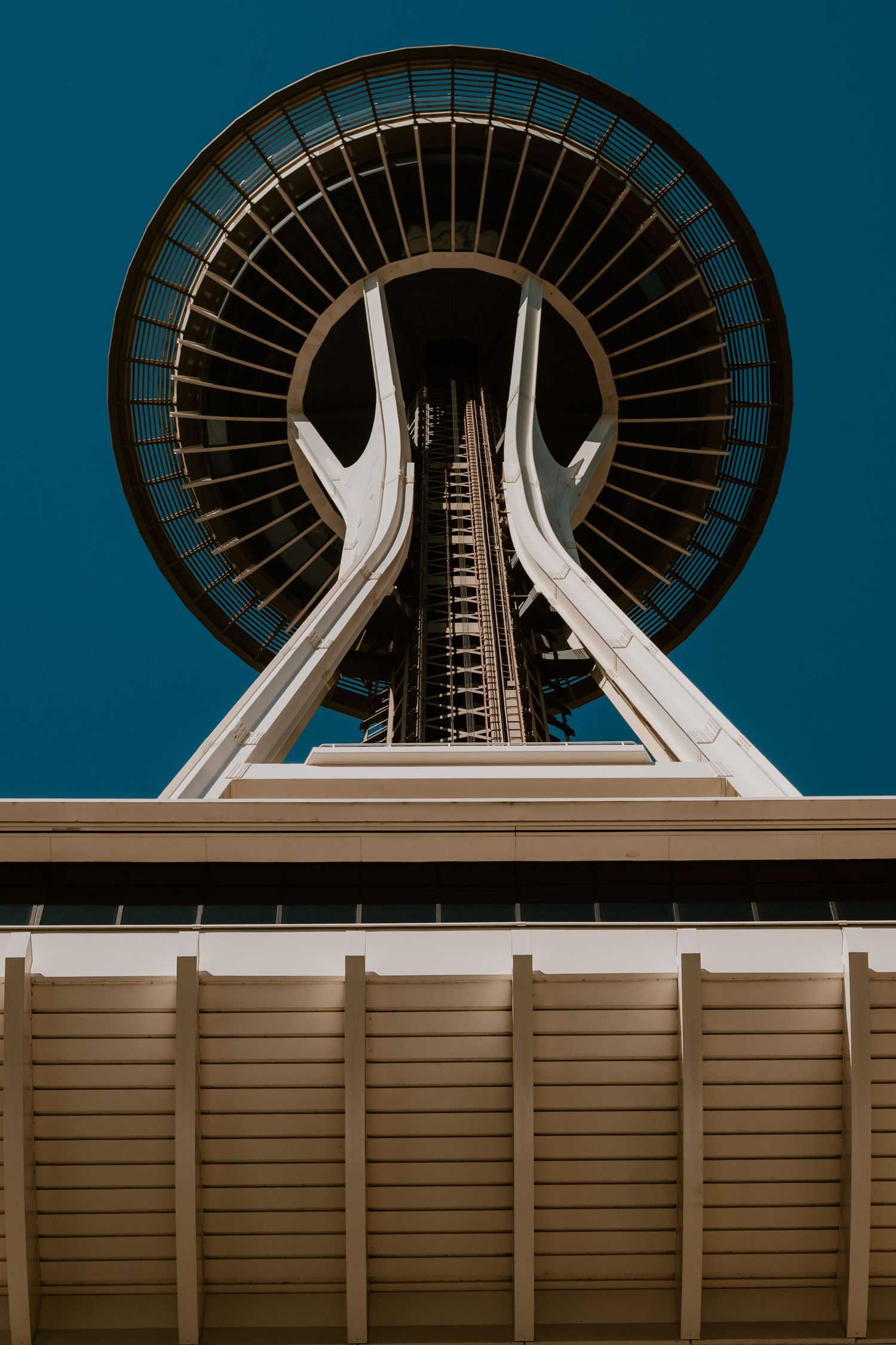 Looking up at Seattle's iconic Space Needle tower against a deep blue sky.