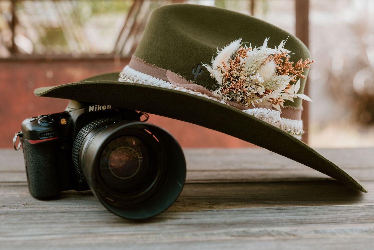Green hat with floral decorations placed next to a professional camera.