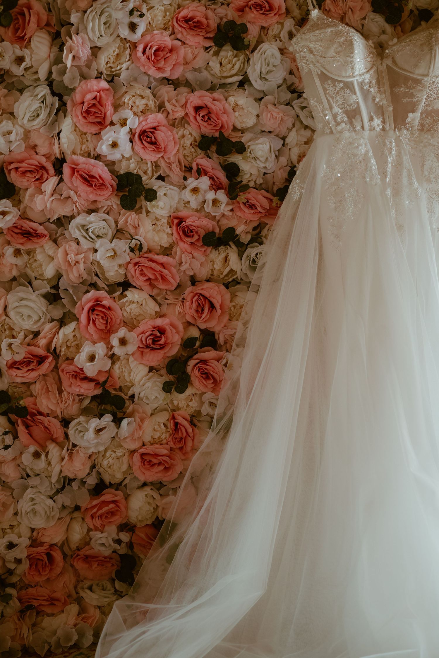 Elegant white wedding dress details against a romantic floral rose backdrop.