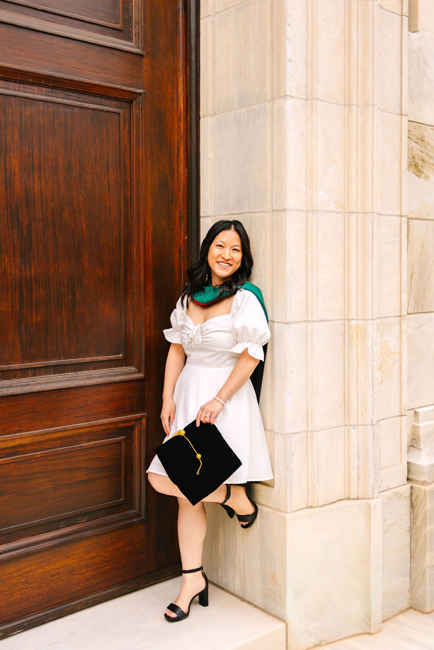 A college grad poses against a school building for graduation photos holding cap at Brown University in Providence, Rhode Island