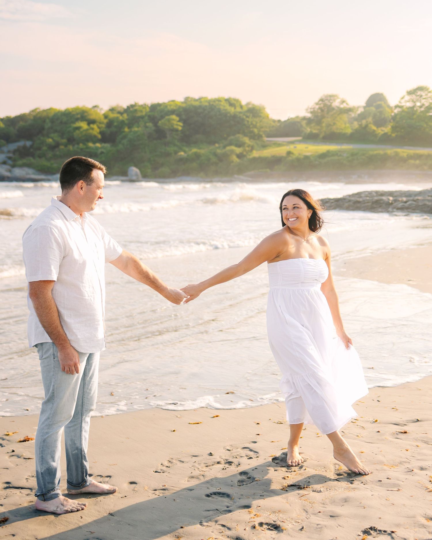 A couple candidly smiles during sunset golden hour engagement photo at Second Beach in Newport Rhode Island