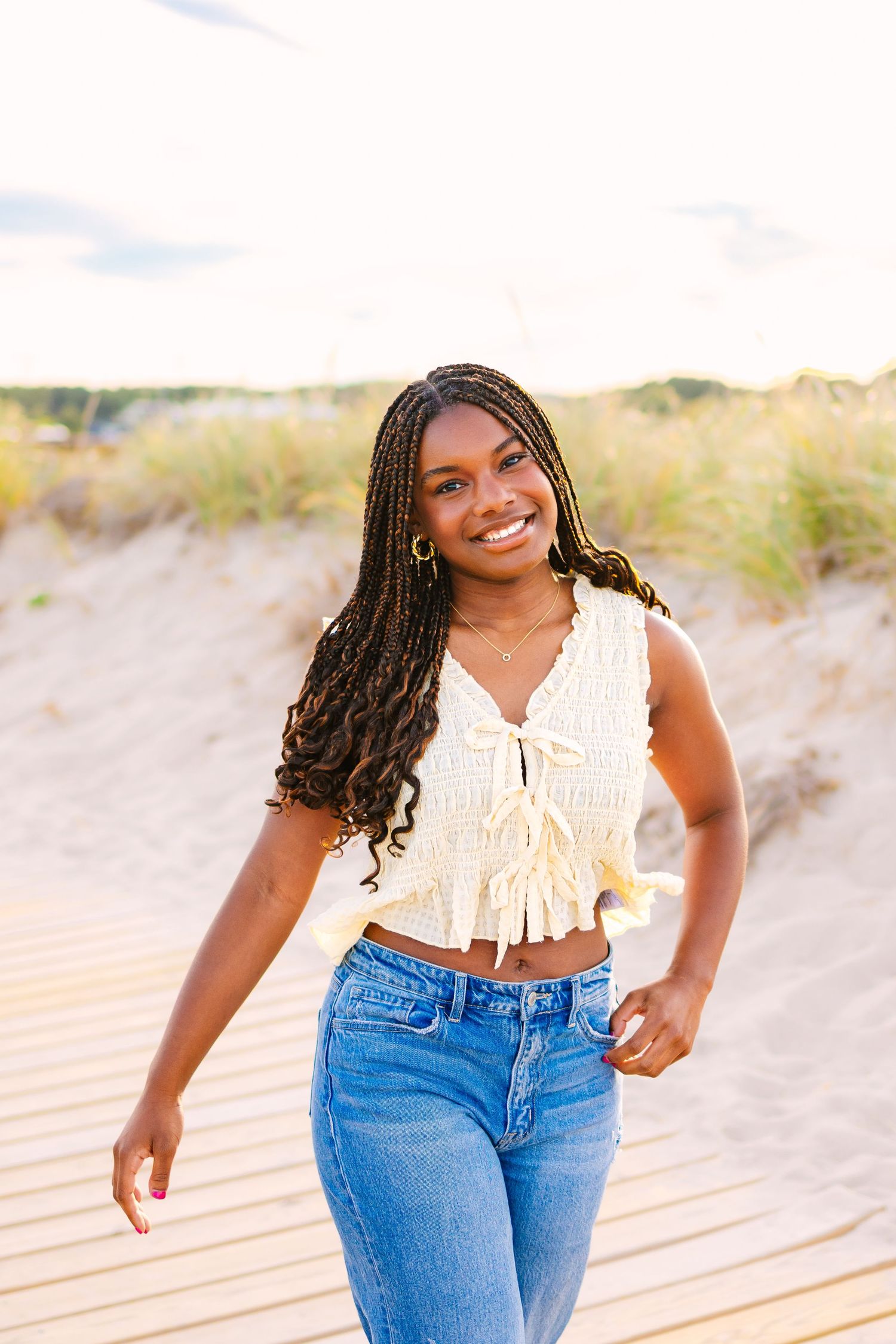 A high school senior takes senior portraits by the sand dunes at sunset golden hour at Scusset Beach in Cape Cod Massachusetts