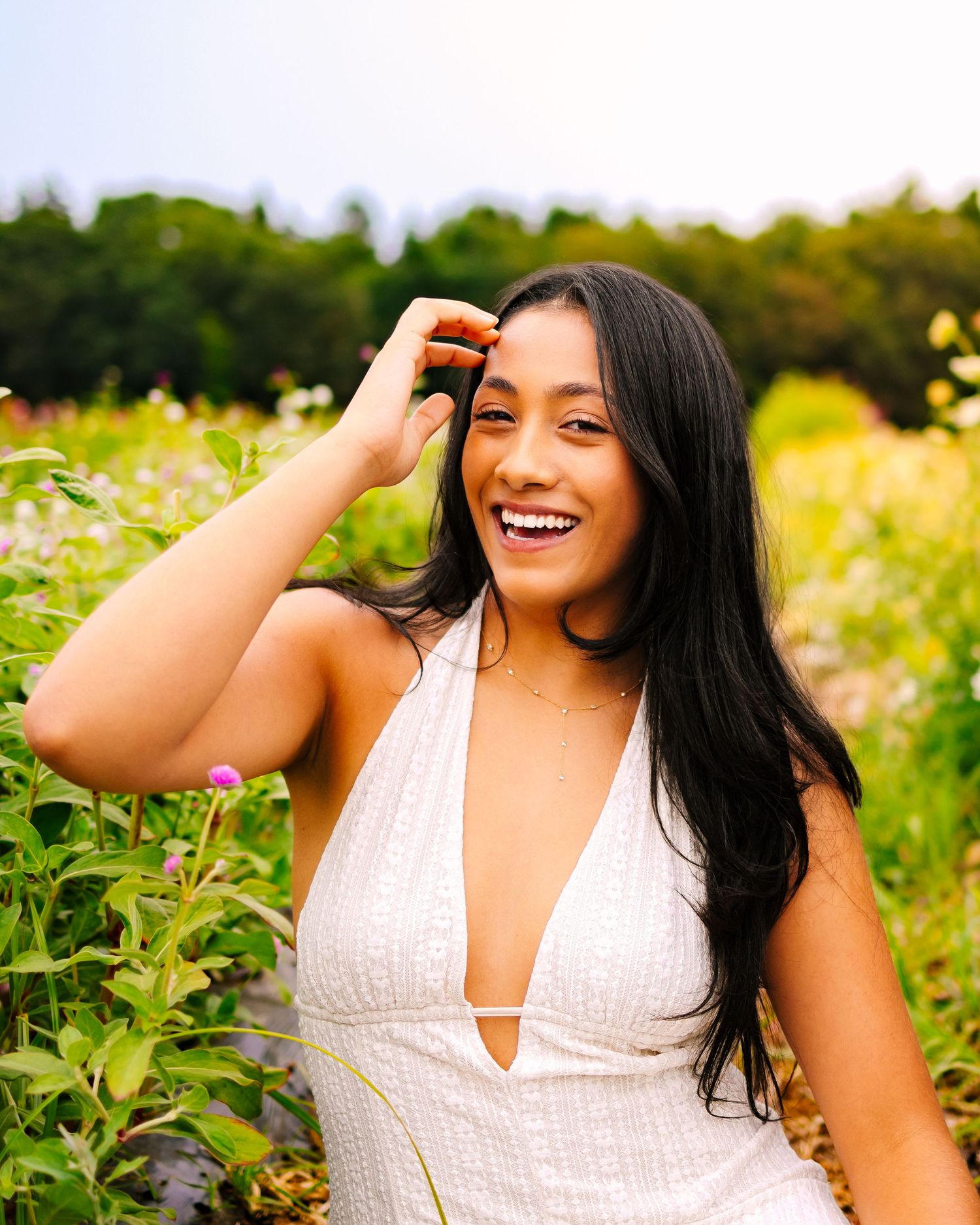 A high school senior poses joyfully in a sunlit field of yellow wildflowers during golden hour at Ward's Berry Farm in Sharon Massachusetts