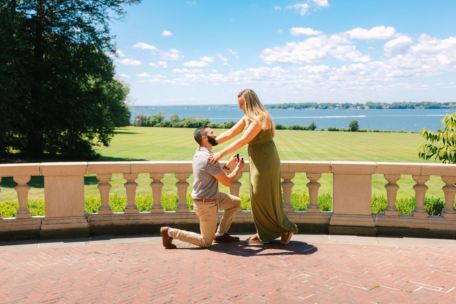Scenic waterfront terrace with stone balustrade overlooking a calm bay on a bright sunny day.