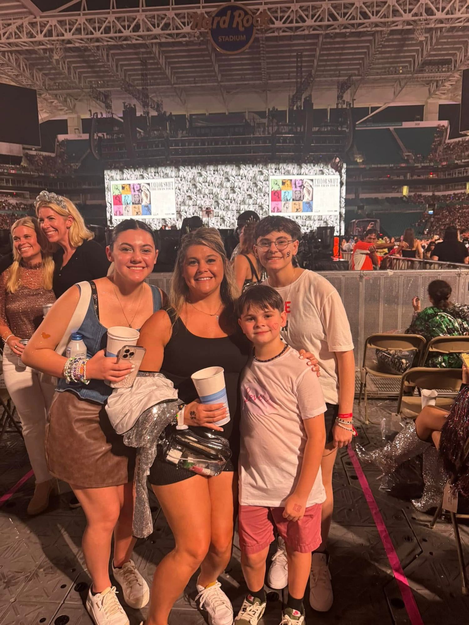 Emma Joyce Photo and her family posing in front of the Eras Tour stage for the Taylor Swift concert in Miami Florida
