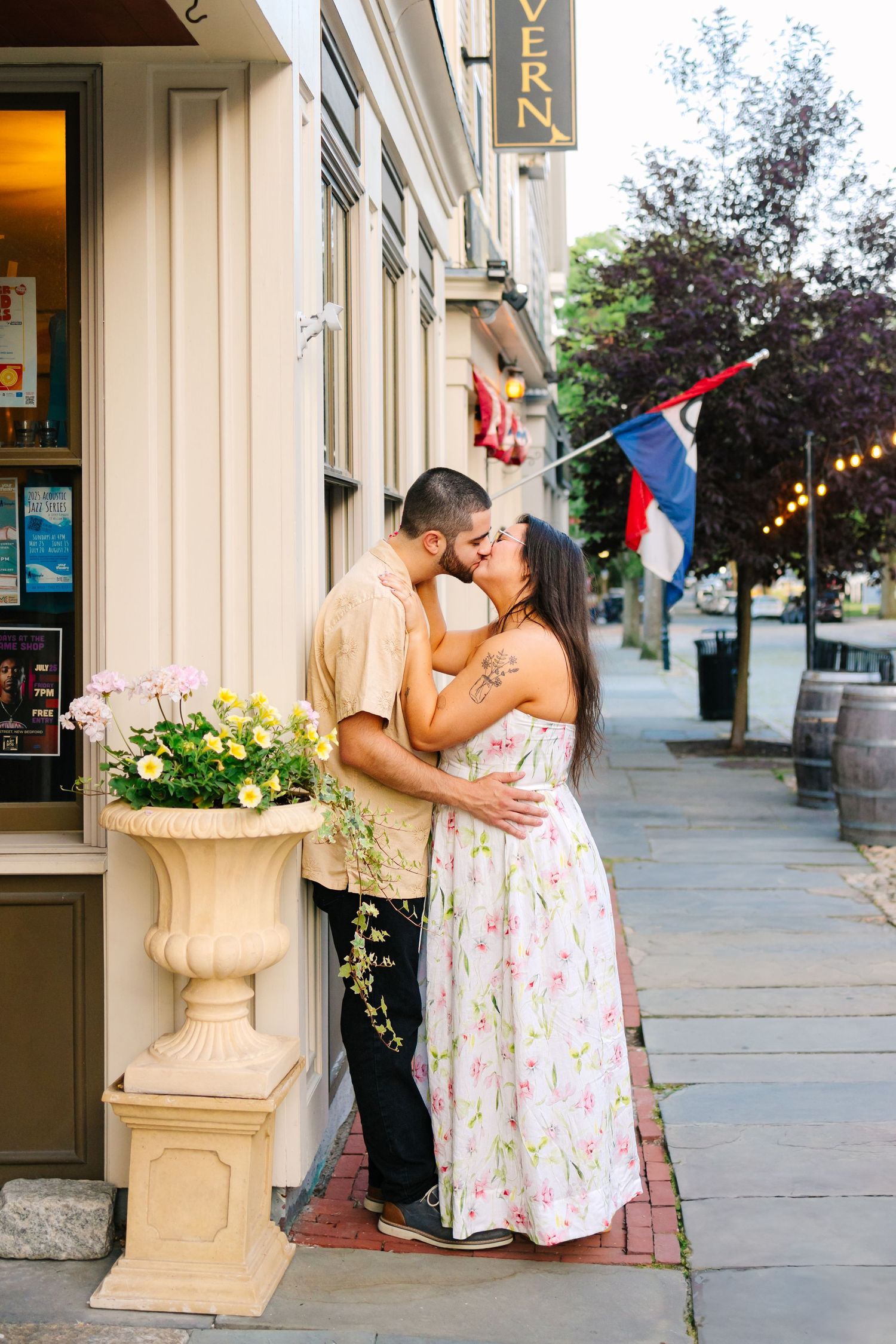 A romantic couple embraces outside a storefront on a city sidewalk for engagement photos in Downton New Bedford Massachusetts