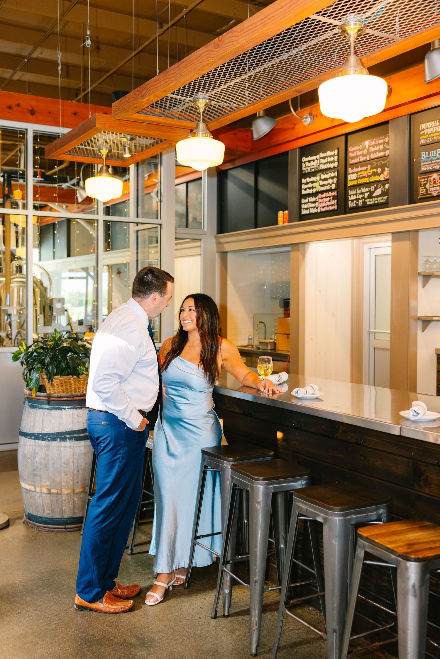 Couple sharing a romantic moment at a rustic restaurant with industrial decor and wooden barrel accents at Newport Vineyards in Rhode Island