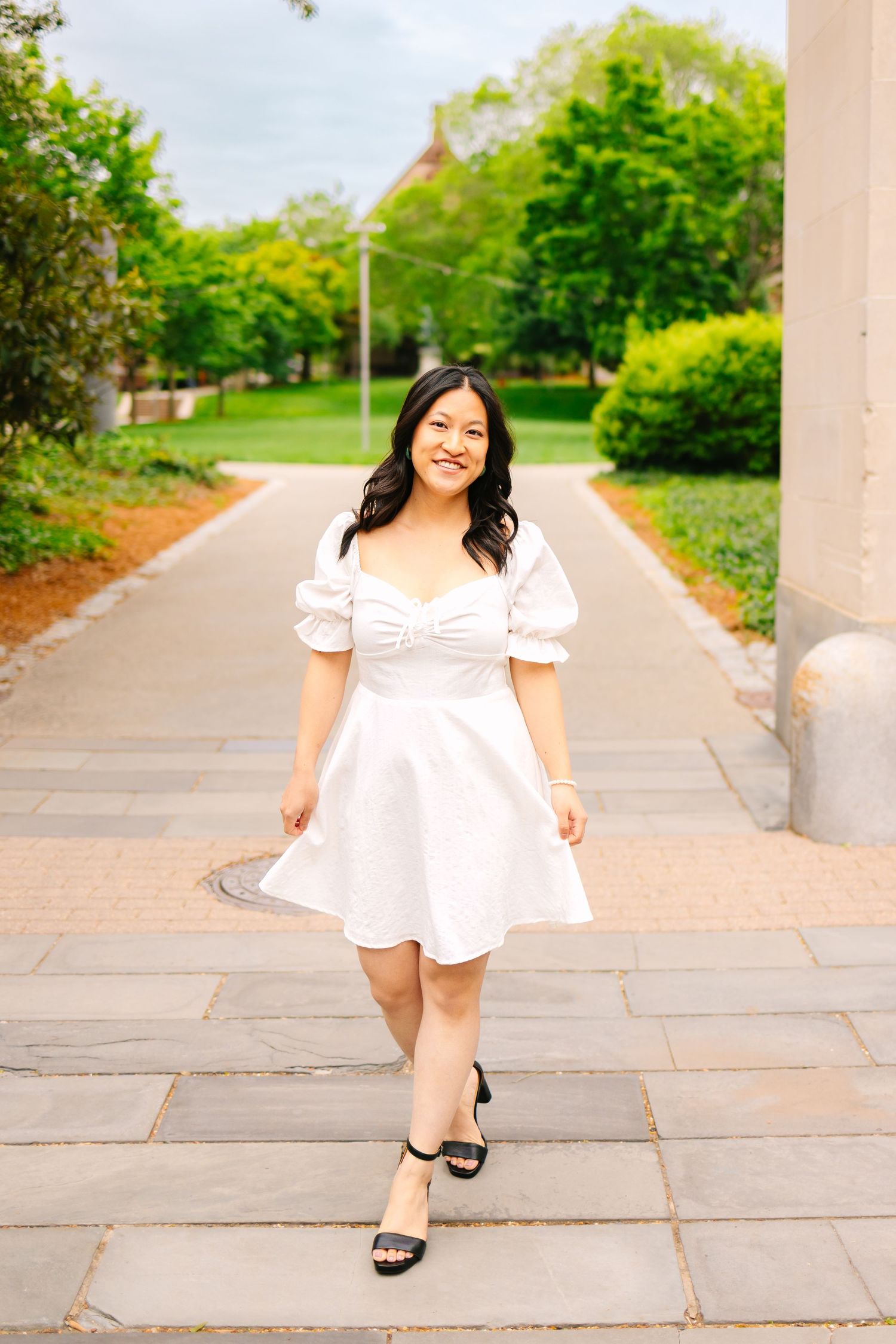 A college senior walking on a stone pathway for graduation photos during sunset at Brown University in Providence Rhode Island