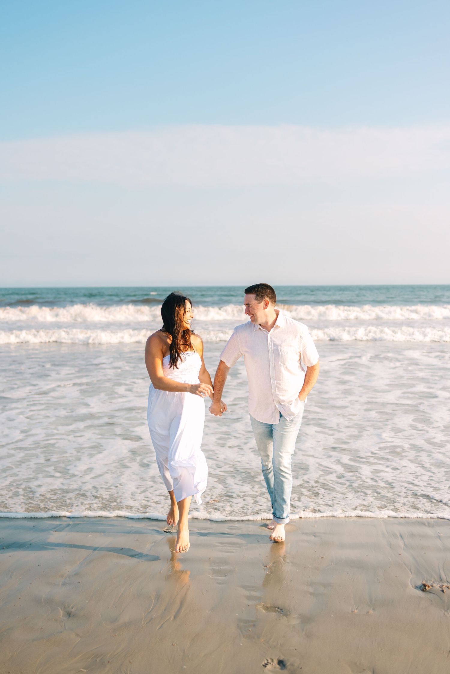 A couple runs along the beach shore at sunset golden hour at Second Beach in Newport, Rhode Island