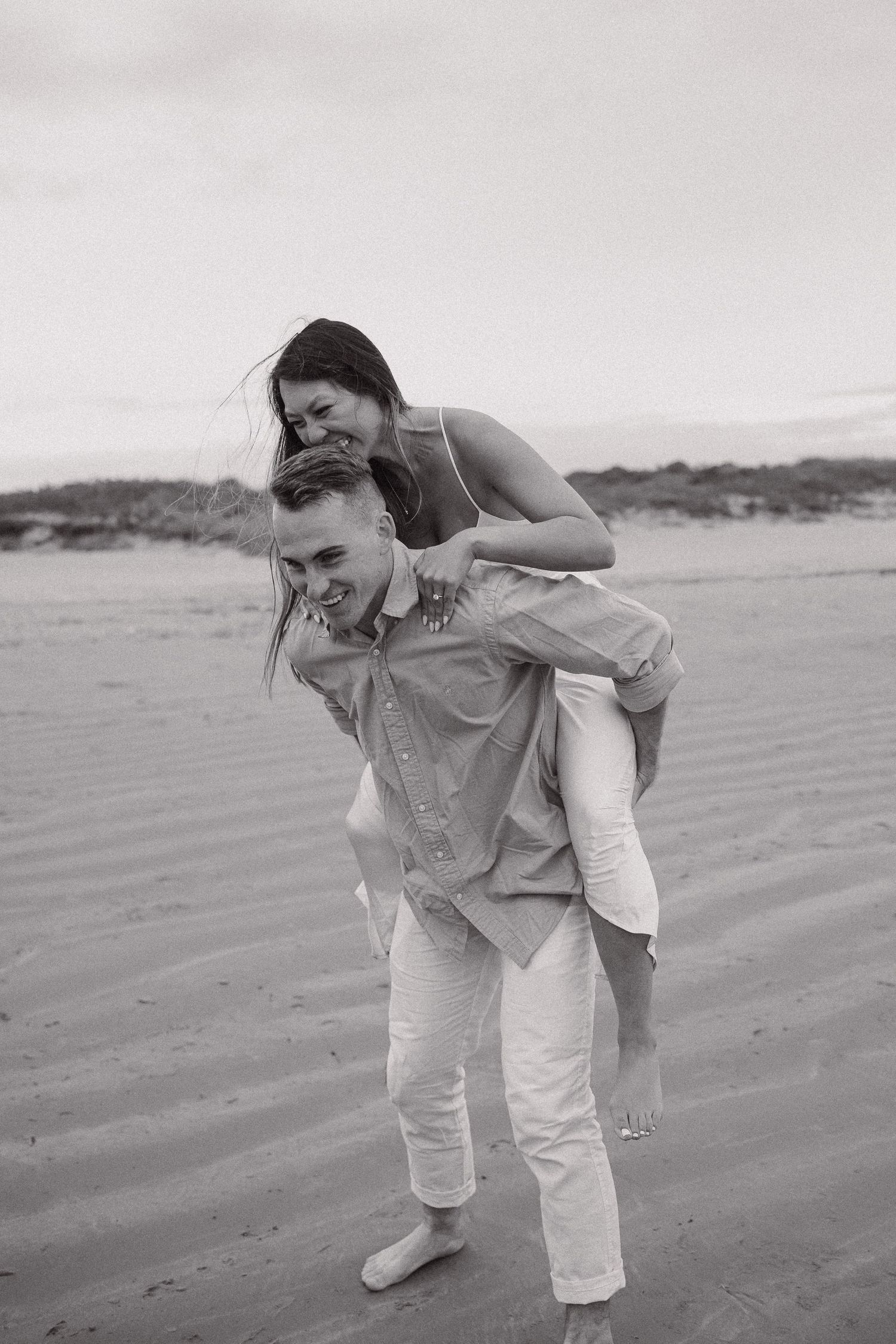 An engaged couple takes playful engagement photos at Second Beach in Newport, Rhode Island