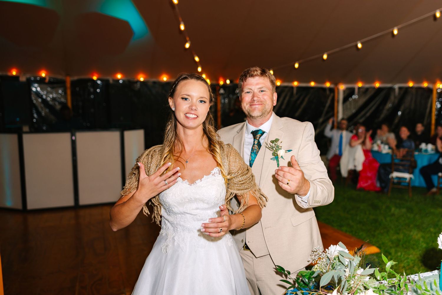 Bride and Groom dance together under string lights at an outdoor evening reception celebration.