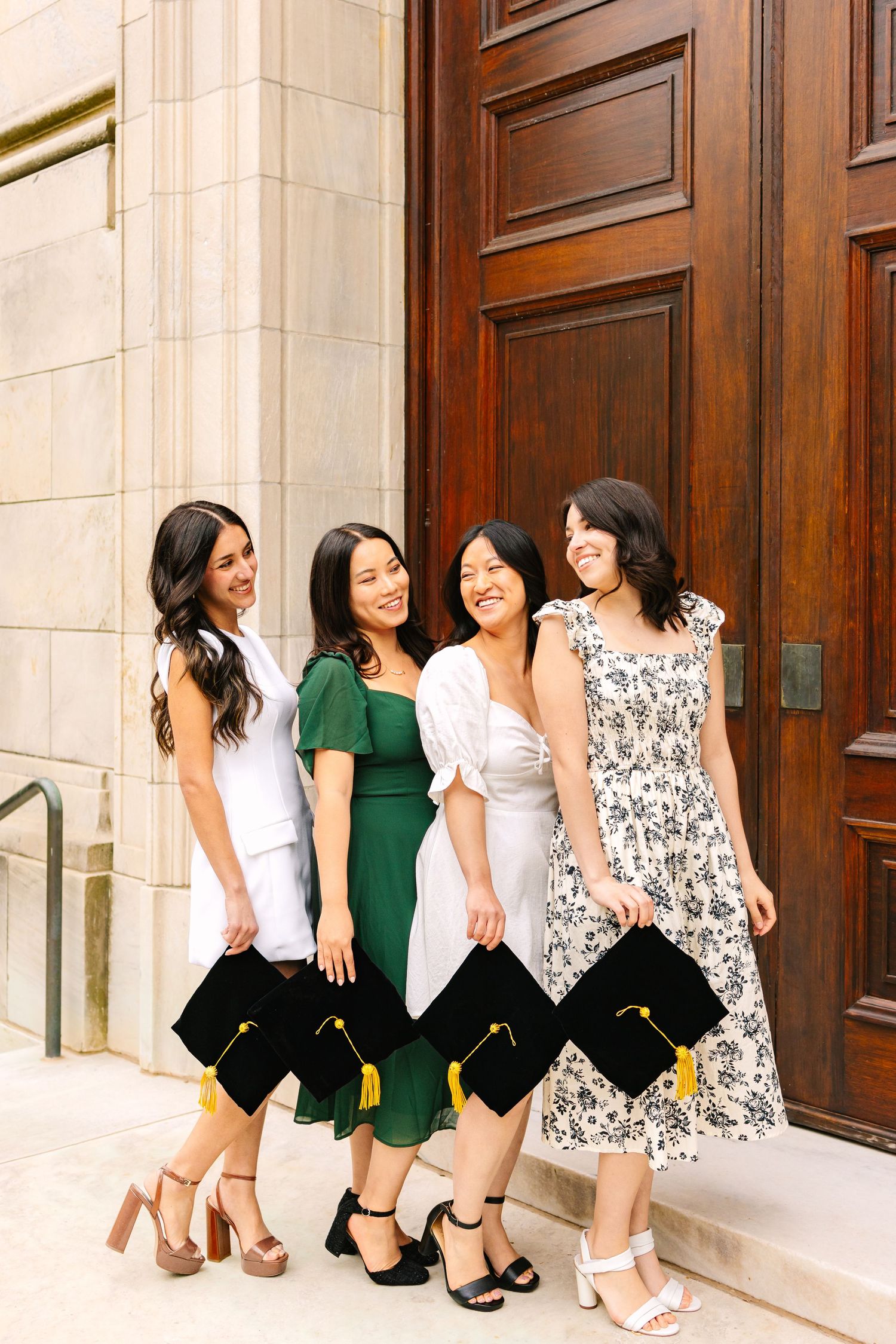 A group of college grads candidly poses in front of school building holding their caps for graduation photos at Brown University RI