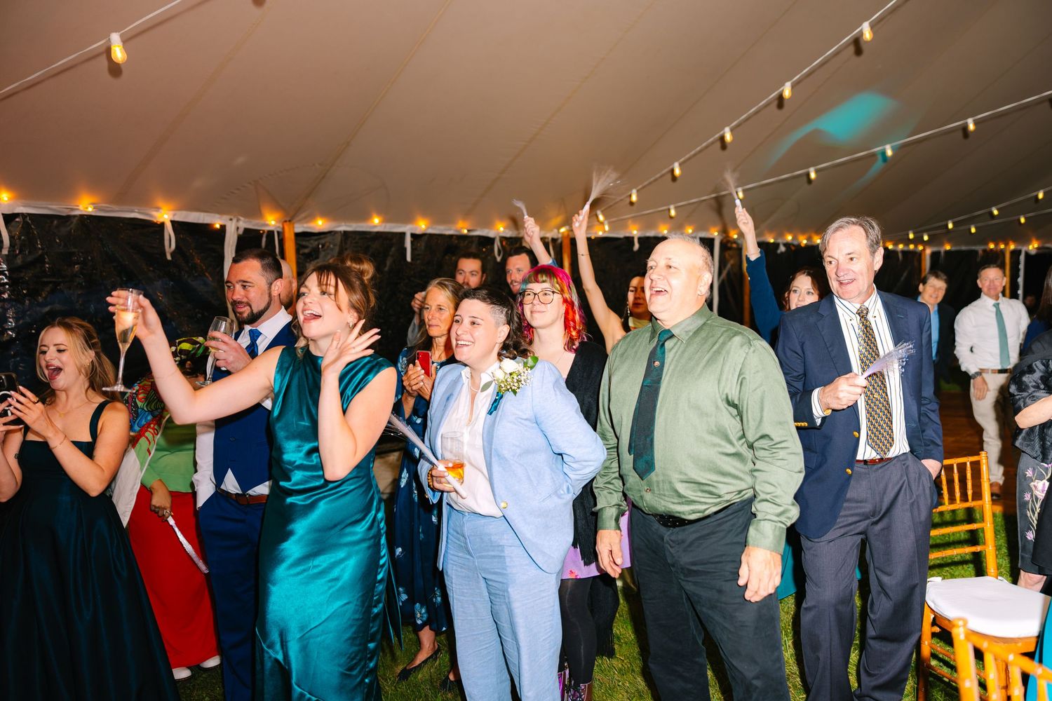 Wedding guests dance and celebrate on a festively lit dance floor during an evening reception.
