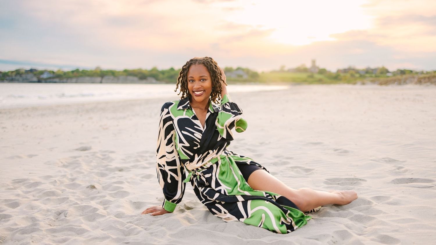 A college grad at sunset sitting on the sandy beach for graduation photos at Second Beach in Newport Rhode Island Salve Regina University