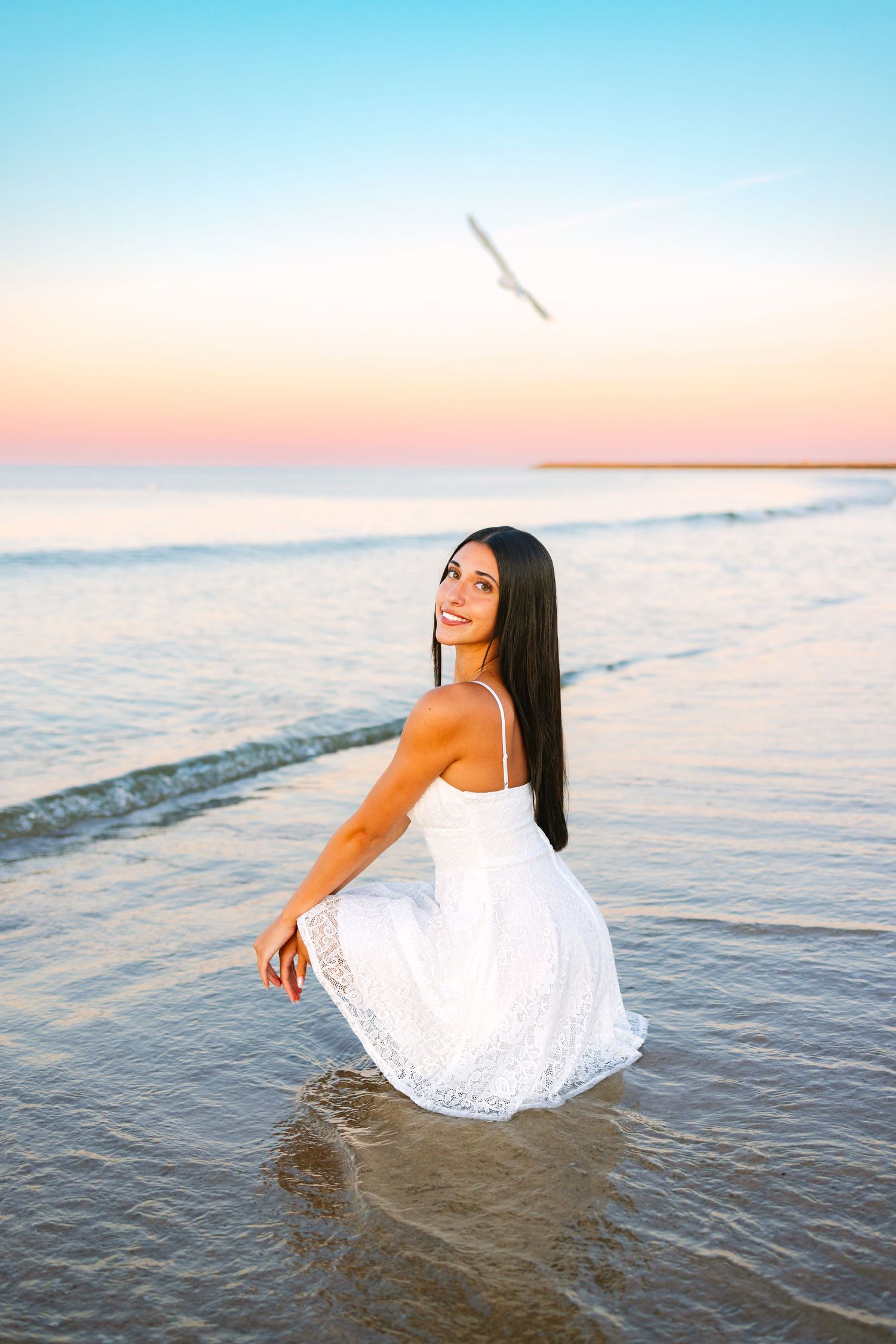 A high school senior posing for senior photos by the shoreline during sunset golden hour at Scusset Beach in Sagamore, Massachusetts