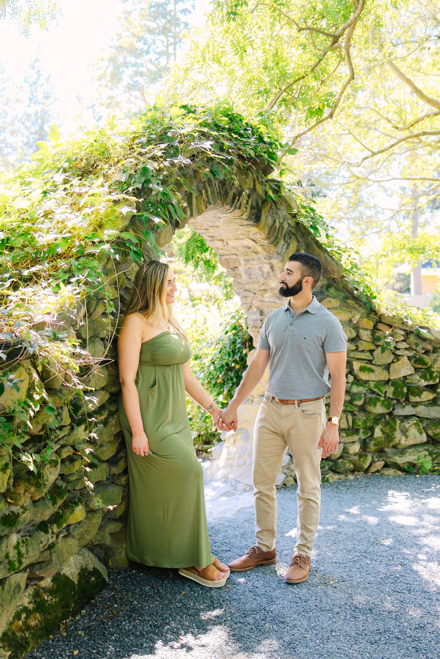 A playful series of photos shows a couple sitting and peeking from behind a lush garden wall.