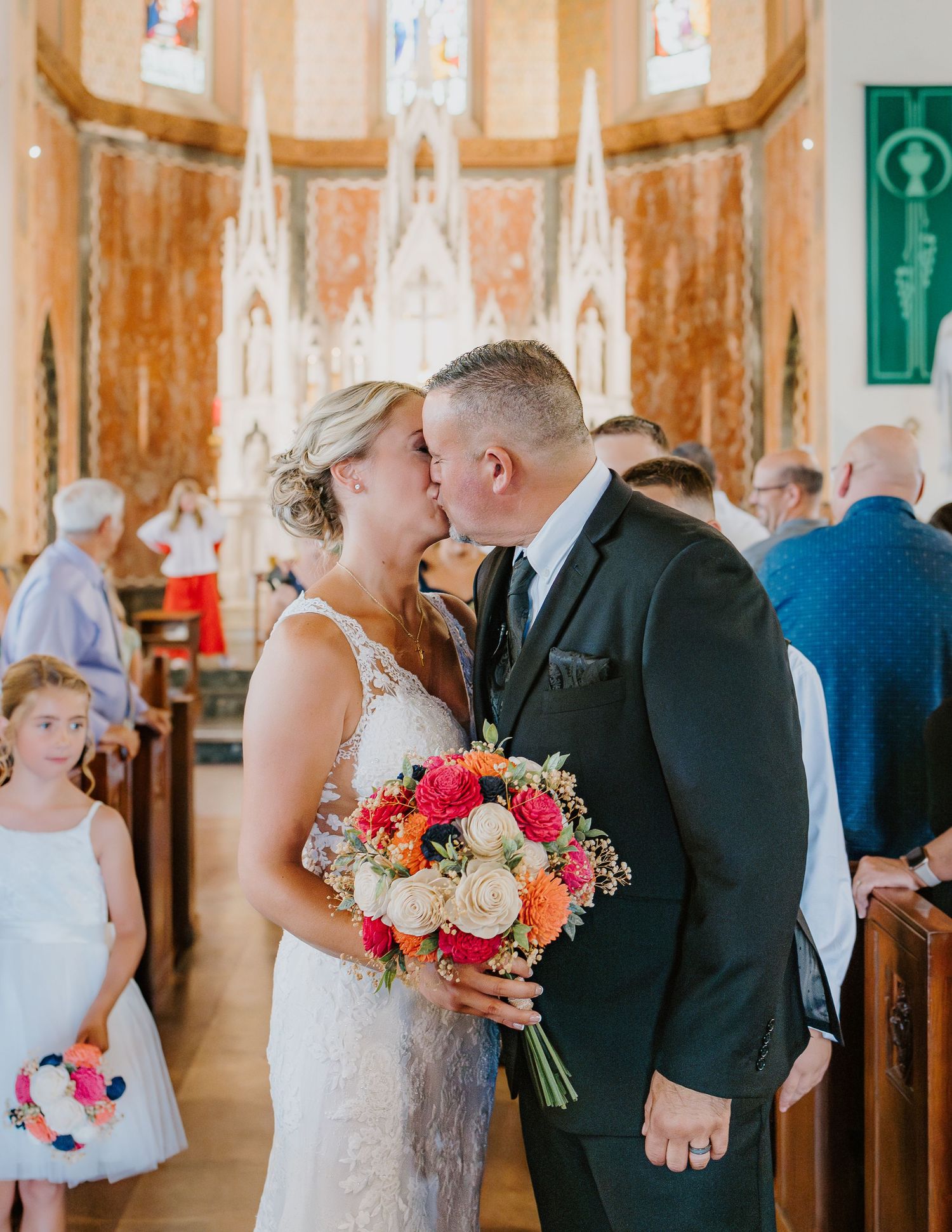 A romantic kiss between a couple during a church wedding ceremony with ornate gothic architecture and floral bouquet in South Coast MA