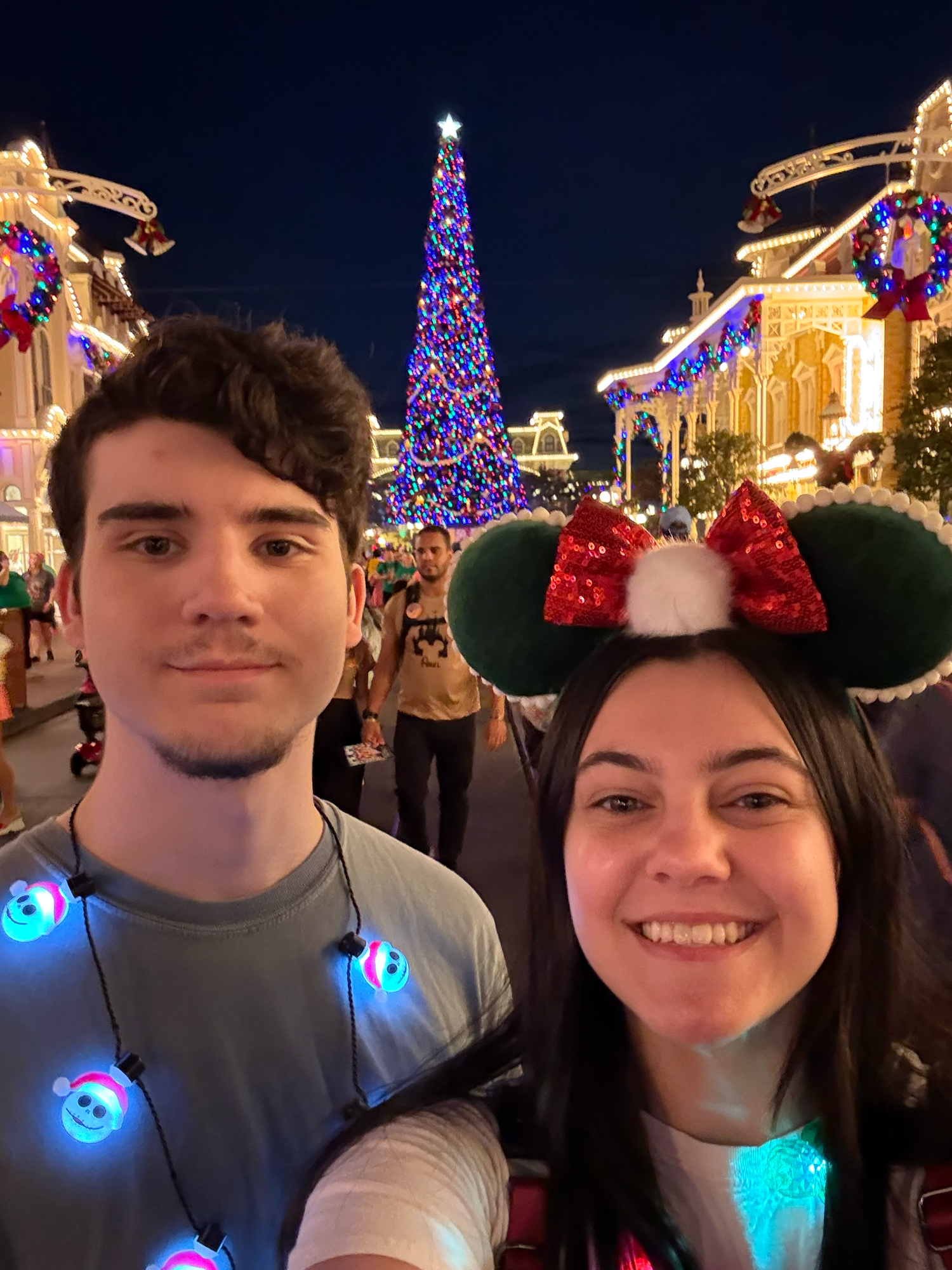 Emma Joyce Photo and her boyfriend at Disney with a large Christmas tree and holiday lights decorating Main Street USA in Orlando Florida