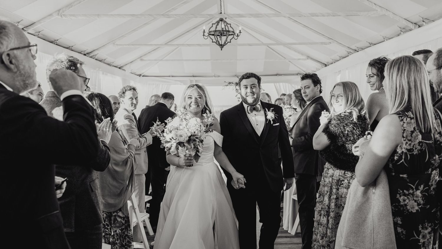 Black and white photo of newlyweds exiting the tented dock ceremony at The Regatta Place in Newport, Rhode Island