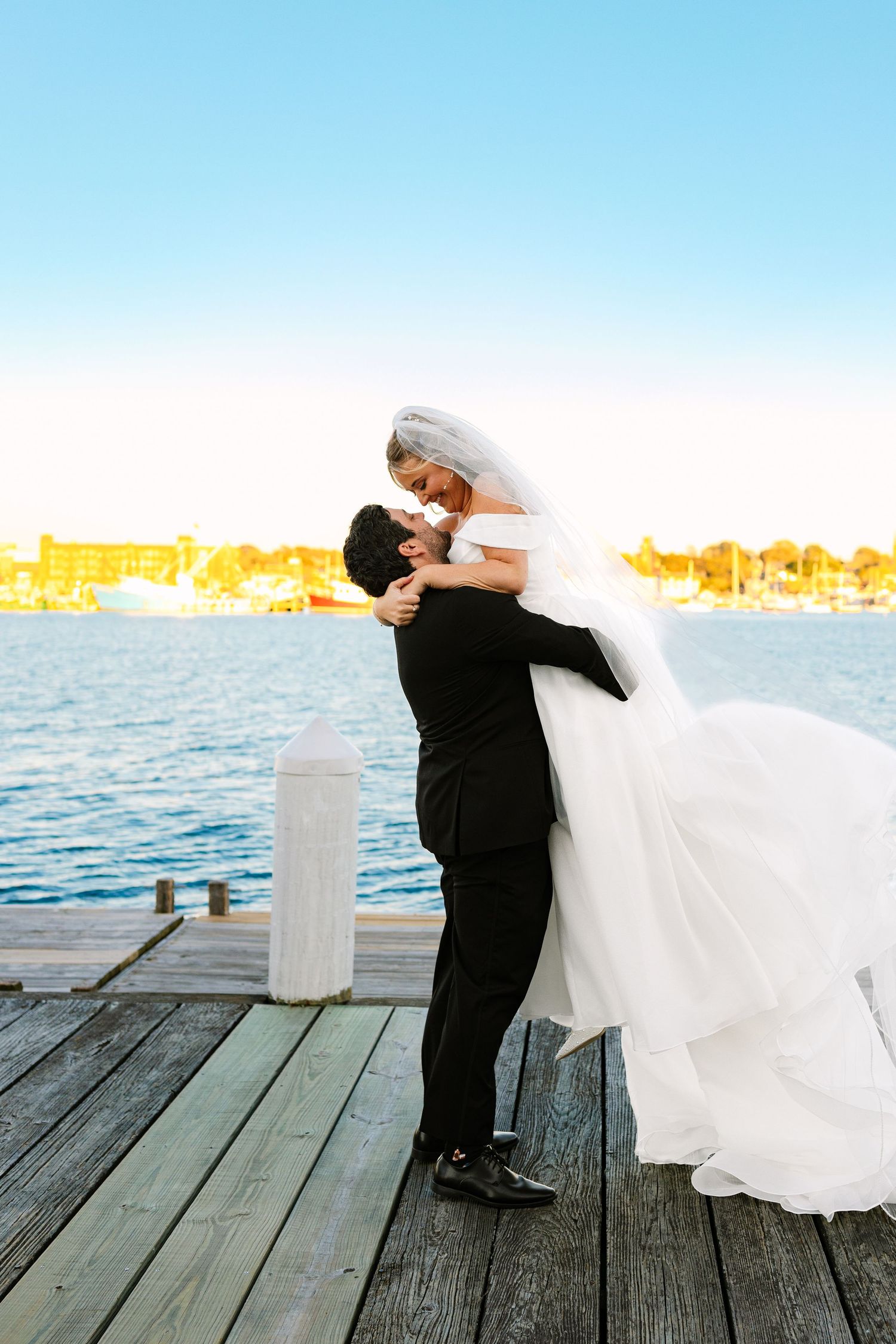 A bride and groom take romantic couples portraits at sunset golden hour at The Regatta Place in Newport, Rhode Island wedding venue