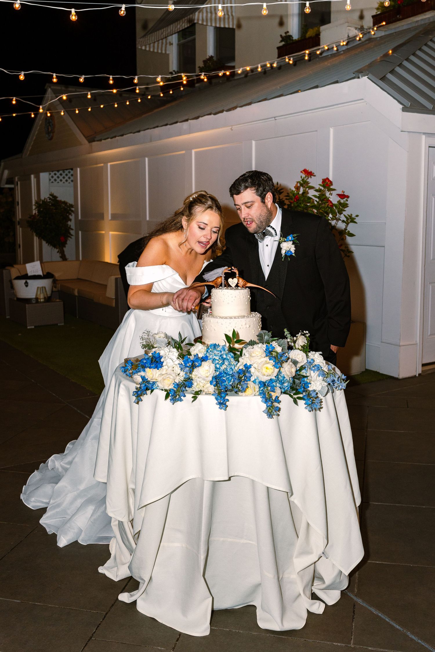 A romantic wedding cake cutting sequence shows a couple sharing sweet moments under twinkling string lights.