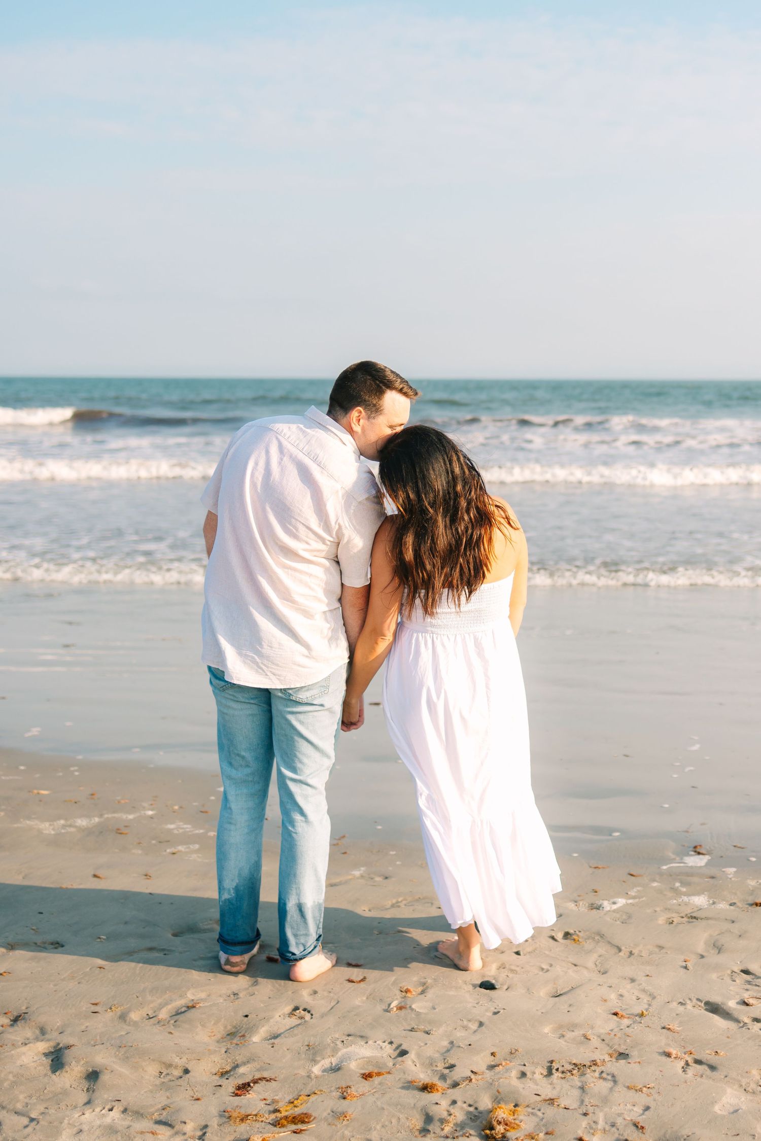 A couple romantically embracing by the ocean shore at sunset golden hour at Second Beach in Newport Rhode Island