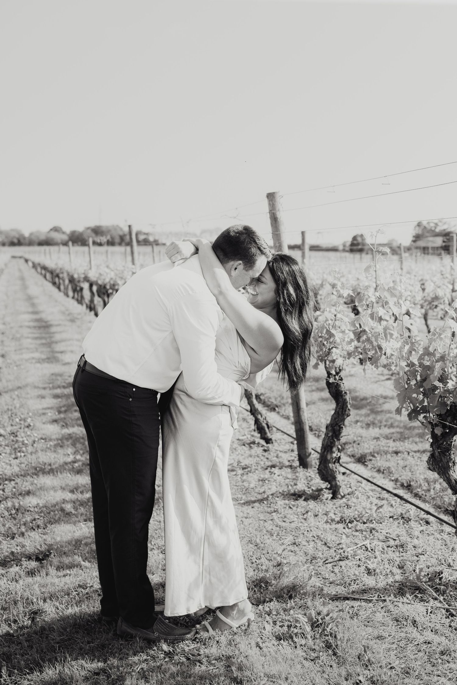 Black and white artistic bridal photo series showing couple embracing in vineyard setting.