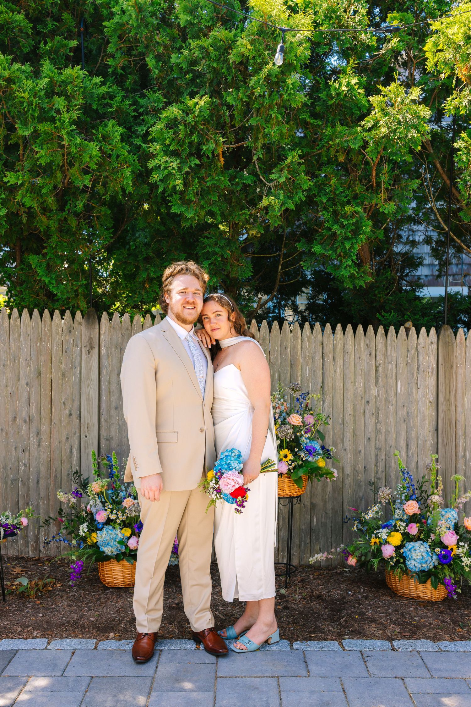 A bride and groom pose editorially during intimate backyard elopement with bright florals in Harwich Port, Cape Cod Massachusetts
