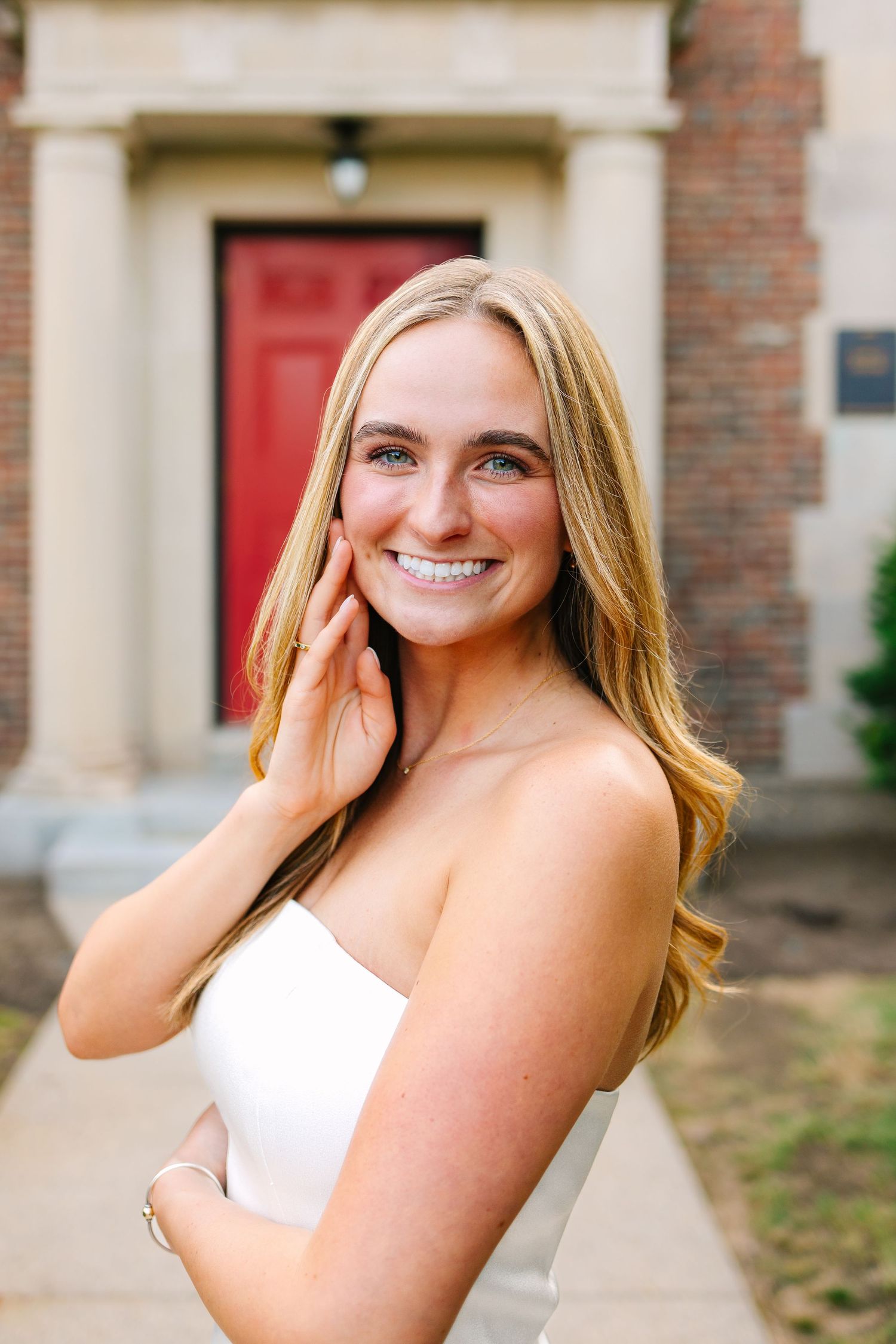 Portrait photo college grad smiling outdoors in front of a brick school building for senior photos at UMASS Boston Massachusetts