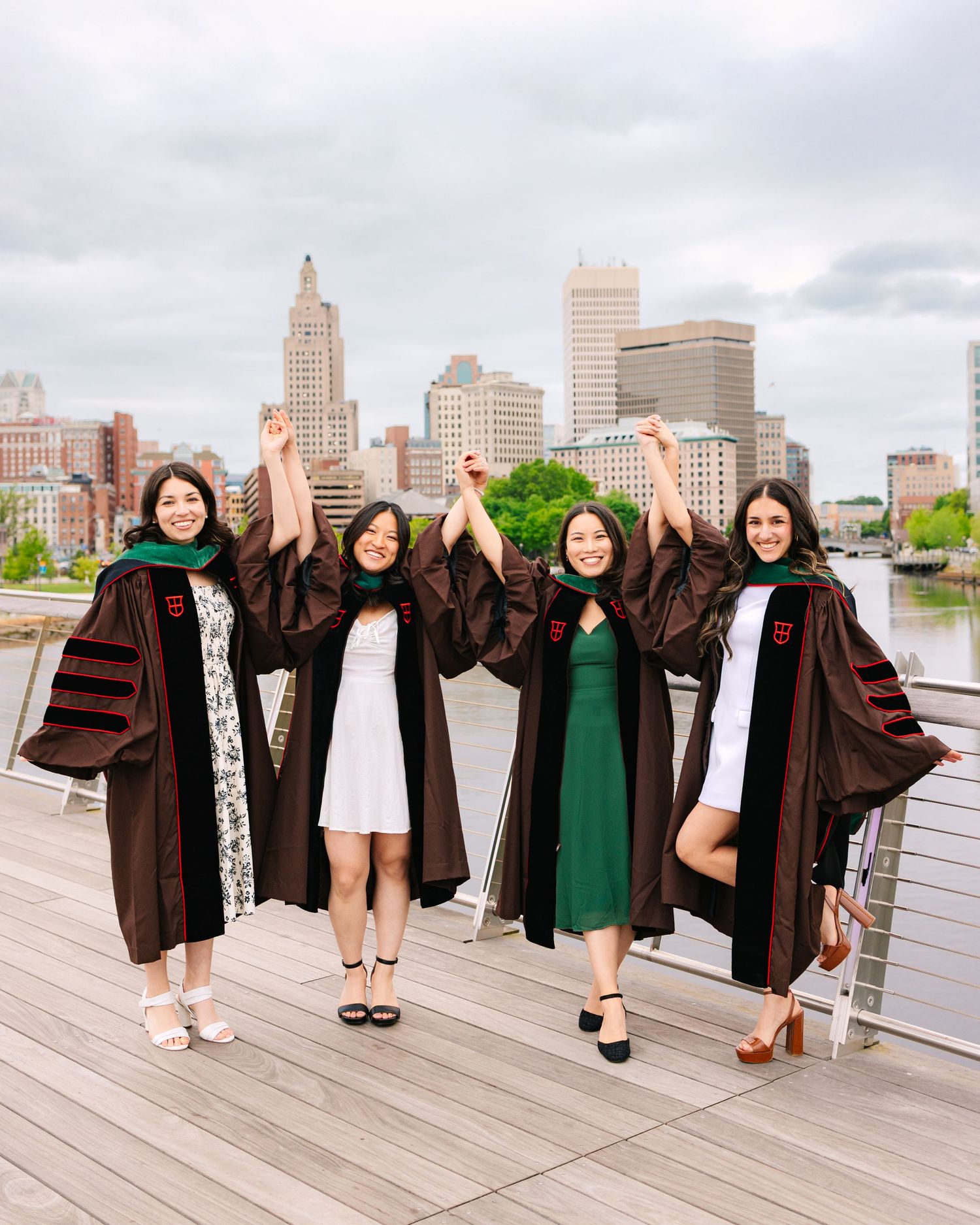 College graduates candidly share excitement during graduation photos on the Providence Pedestrian Bridge for Brown University in RI