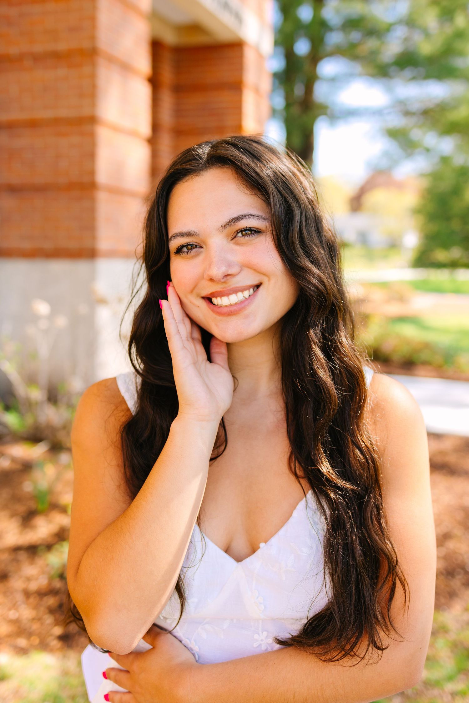 A college grad posing by their school building for graduation photos at Worcester State University in Worcester Massachusetts
