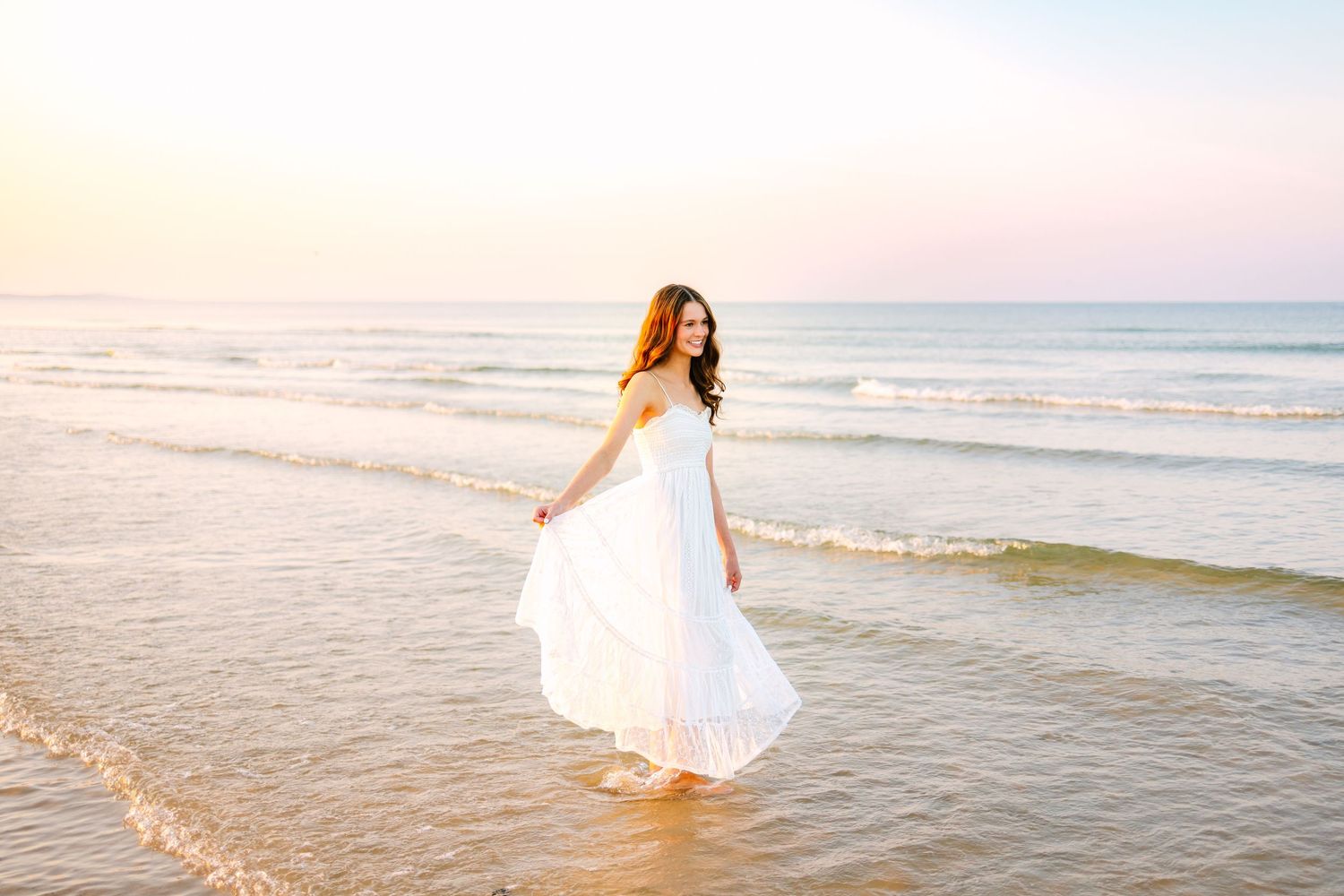 A high school senior taking senior portraits on the shoreline during sunset golden hour at Scusset Beach in Cape Cod Massachusetts.