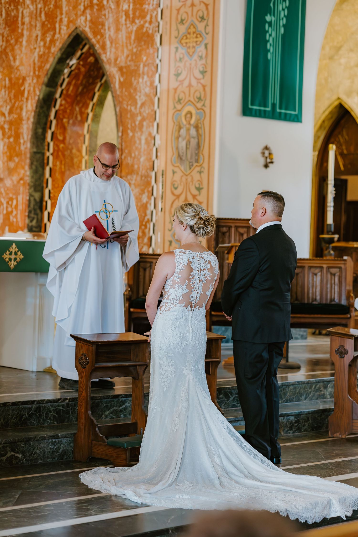 A wedding ceremony takes place in a beautiful church with ornate architecture and decorative arches and pillars in South Coast Massachusetts