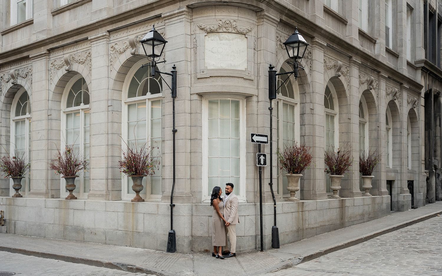 Romantic engagement photo of couple embracing on corner of classic stone building.