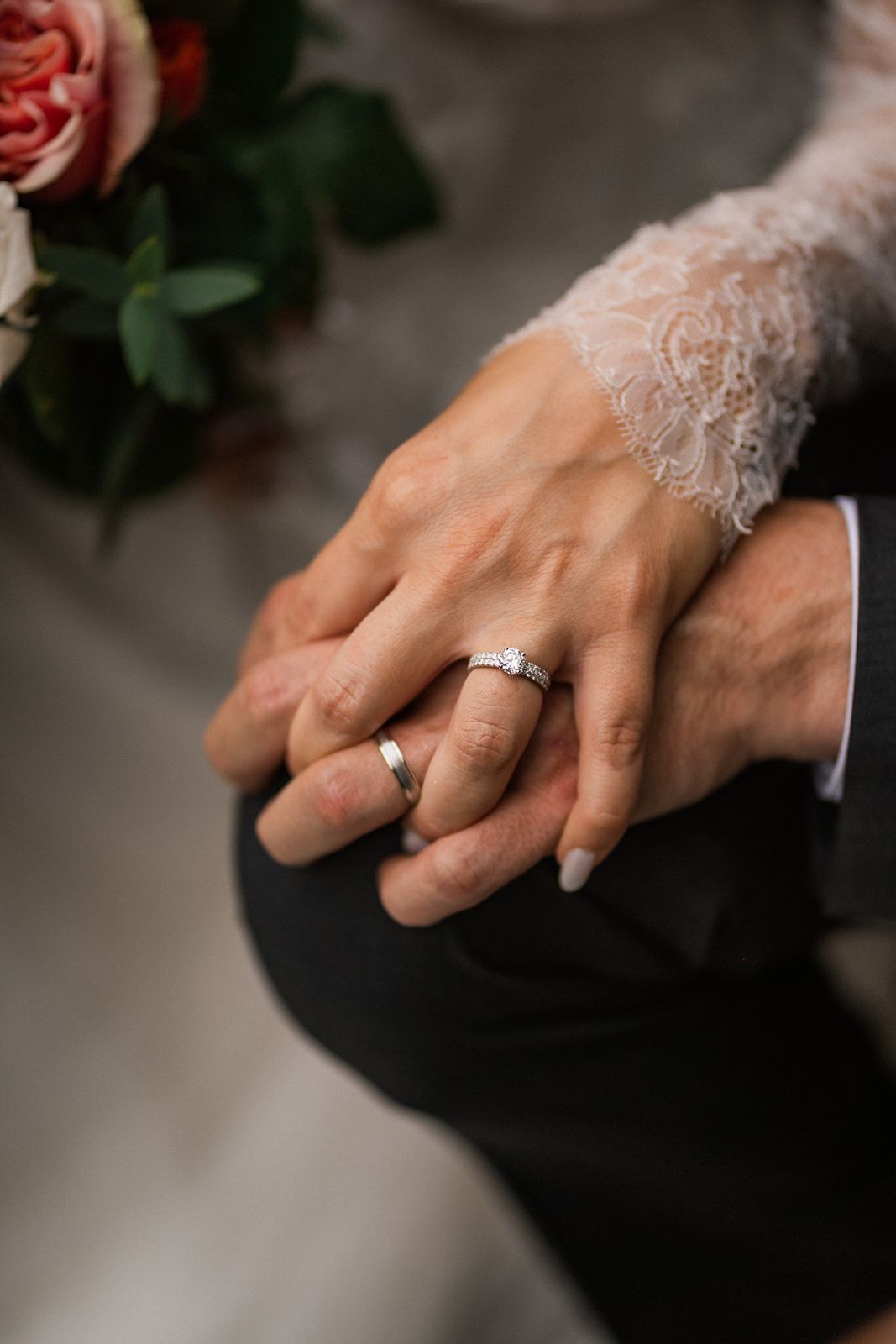 Close-up of hands with wedding rings and delicate lace detail.