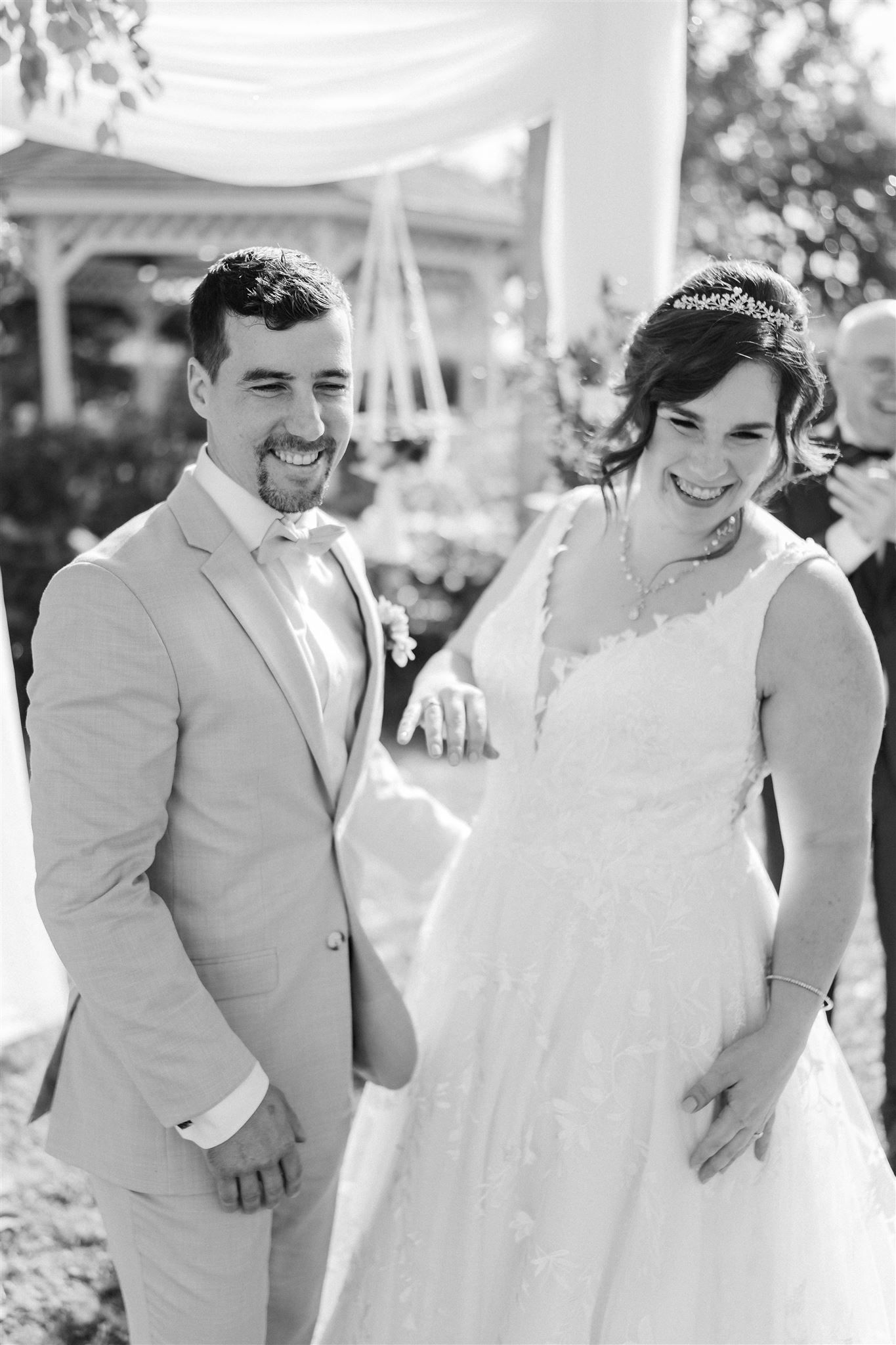 Black and white wedding photo capturing a joyful candid moment outdoors.
