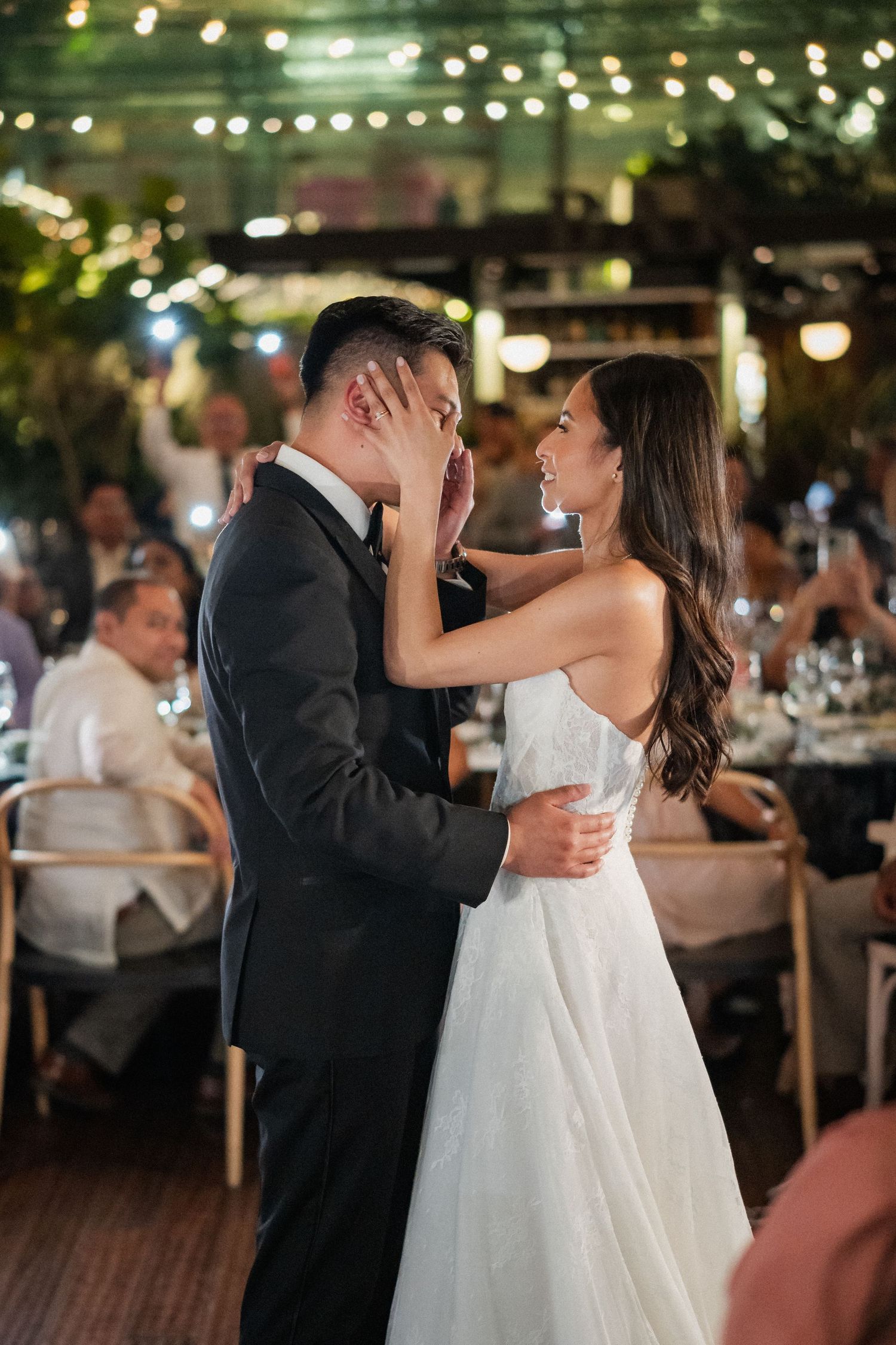 A couple shares an intimate moment during their first dance at an outdoor wedding reception.