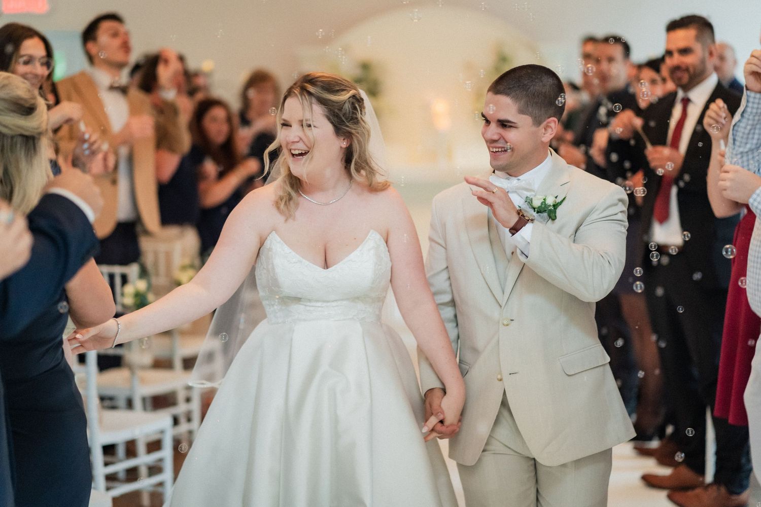 Joyful newlyweds celebrate their first dance surrounded by guests at an indoor wedding reception.