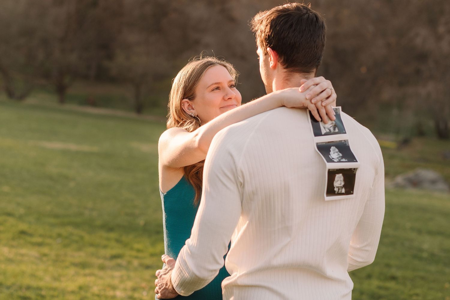 A couple dances together in a romantic outdoor setting at sunset with a golden glow in the background.