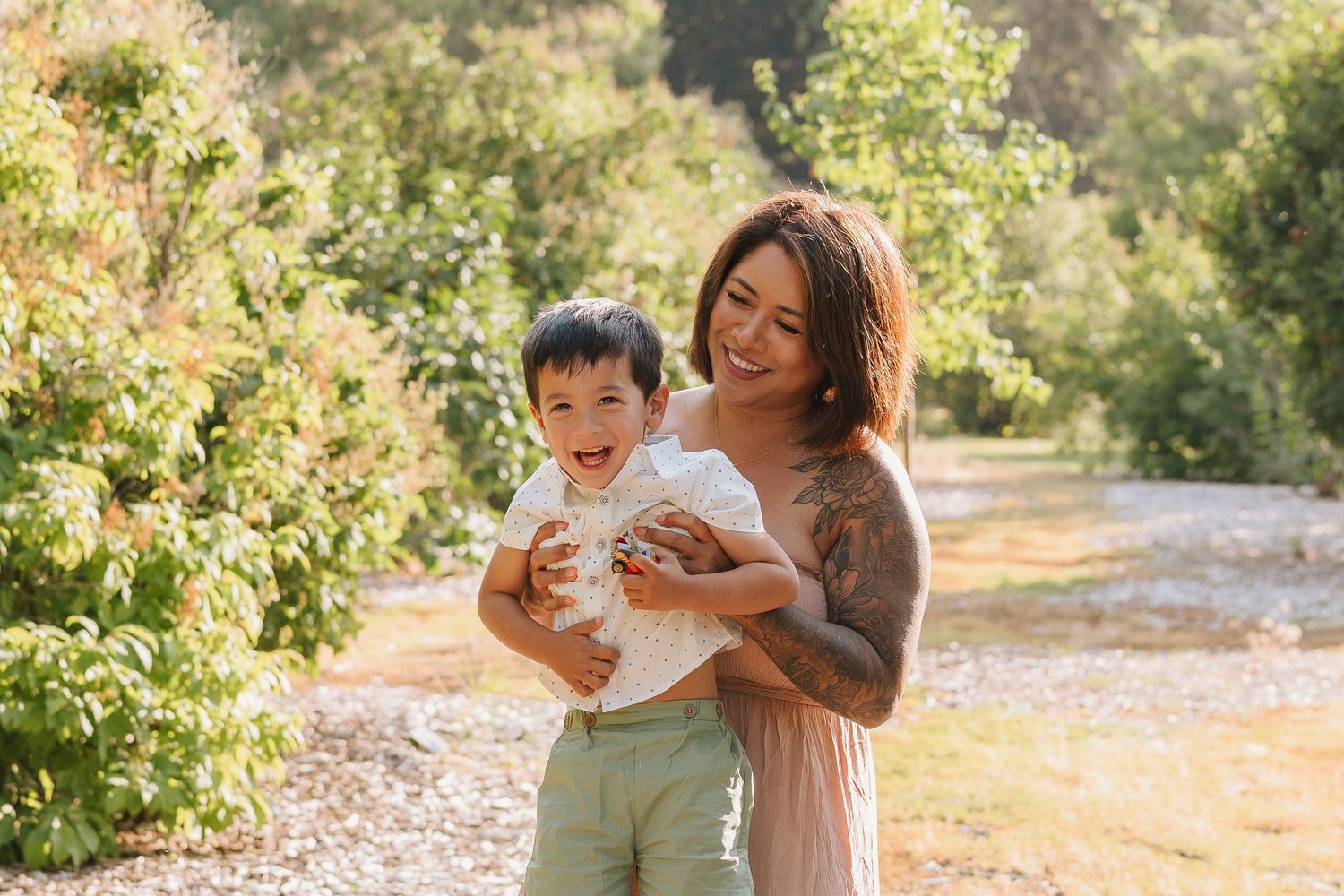 Family enjoying a tender moment together in a sun-drenched garden setting during golden hour.