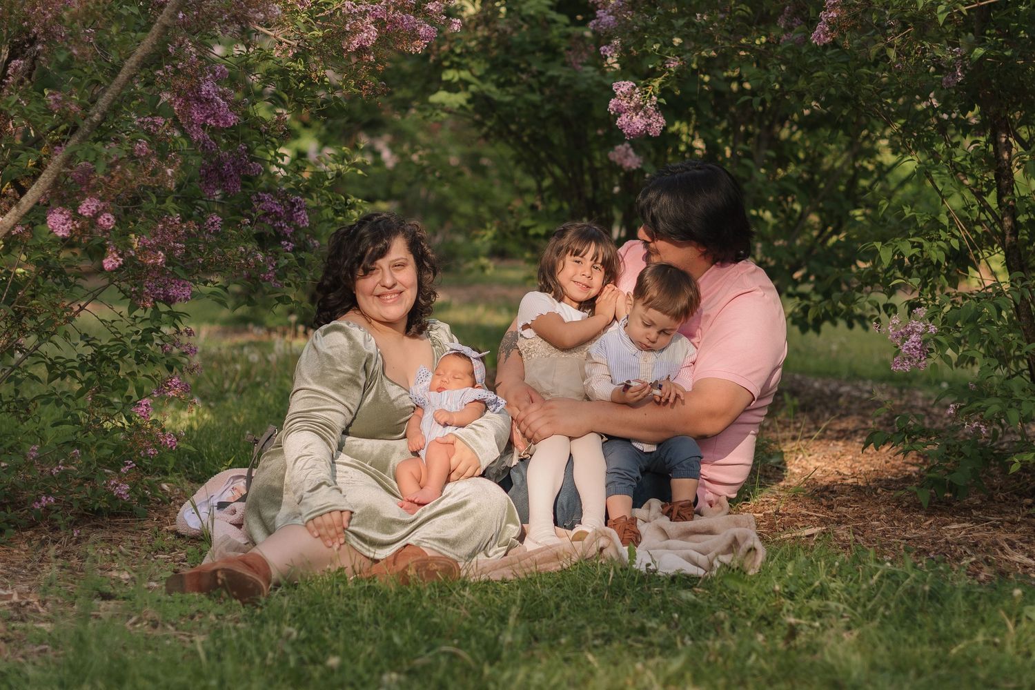 Family enjoying a picnic under blooming pink trees in a spring garden setting.